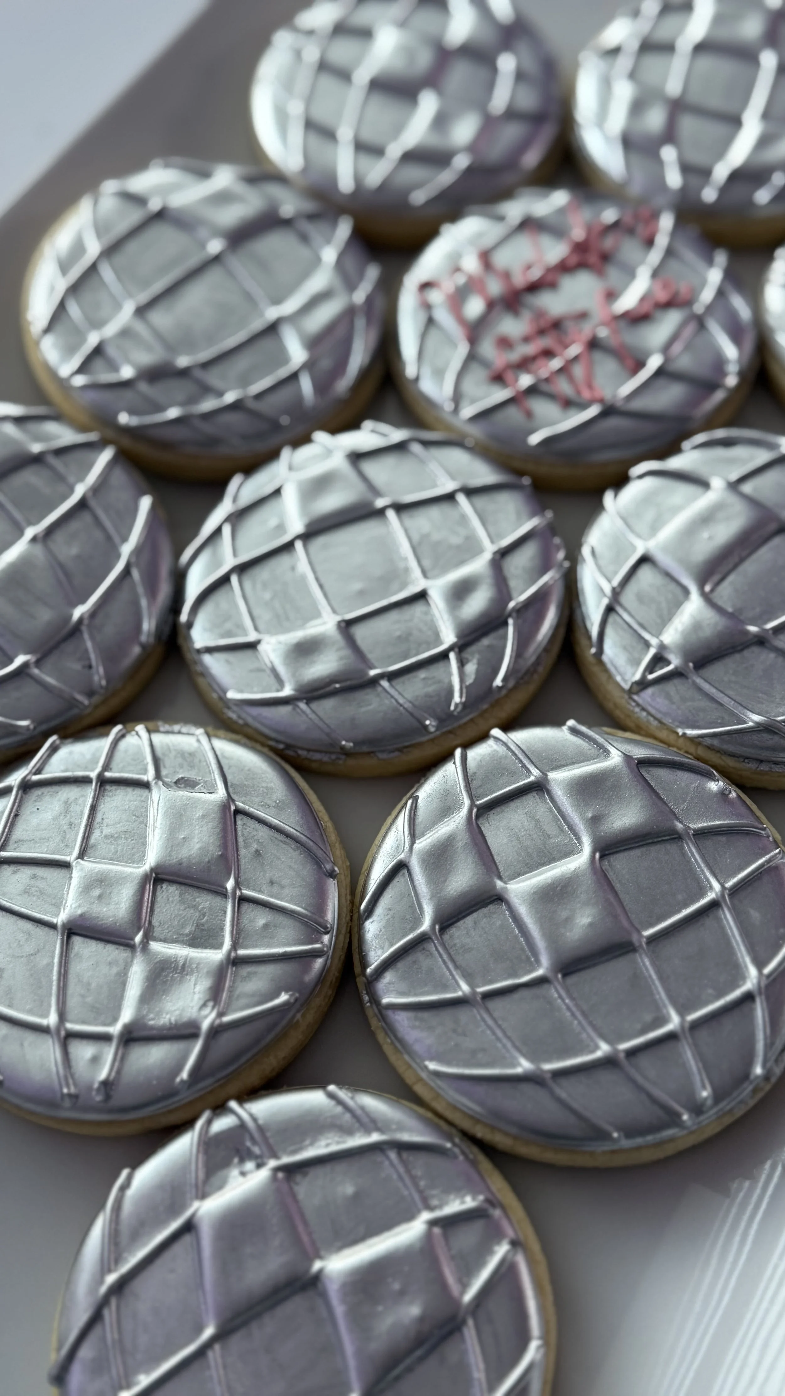 Cookies with silver, purple, and pink icing decorated with geometric patterns and a star design.