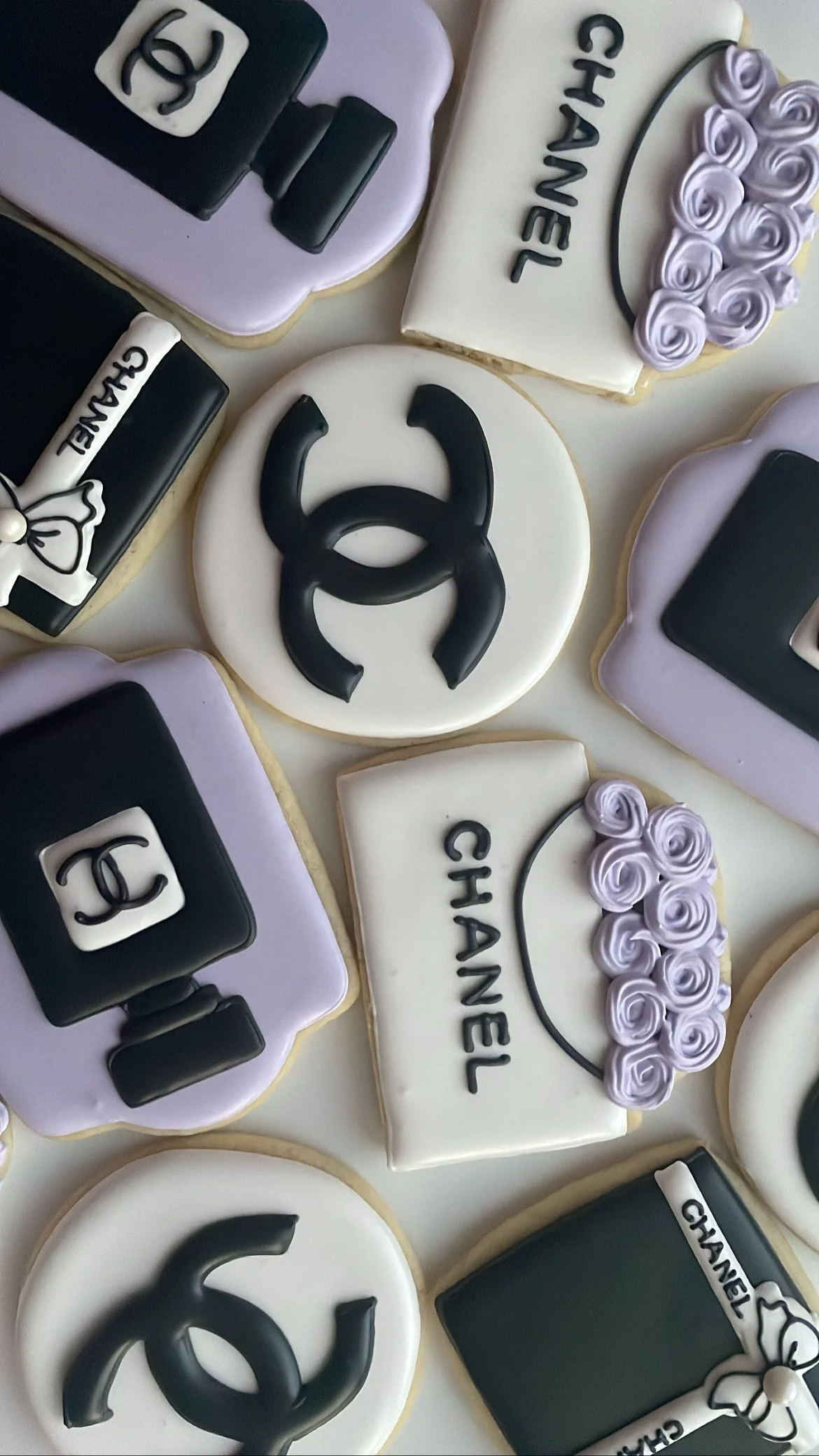 Assorted Chanel-themed cookies decorated with the brand's logo, black and white colors, and floral designs.