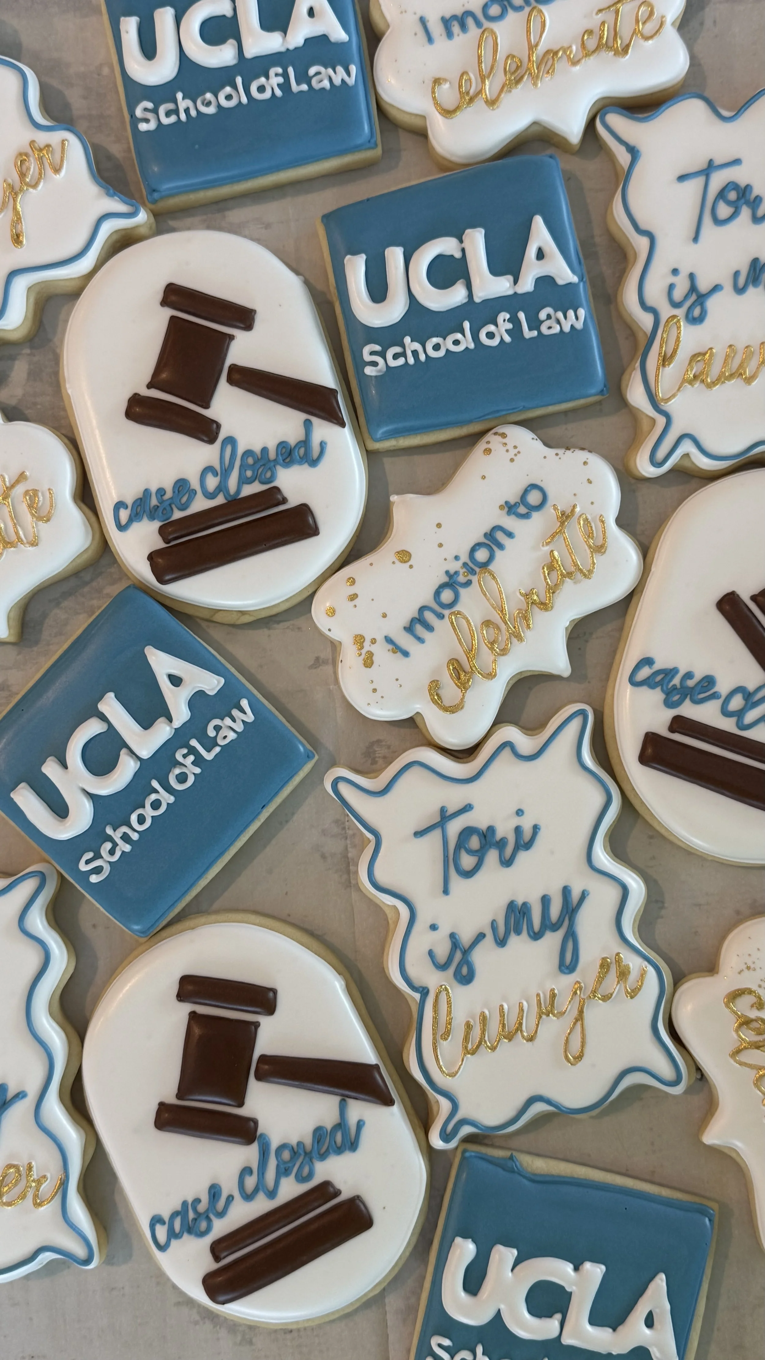 Cookies decorated with messages about UCLA School of Law, some with blue and white icing, some with gold accents, and some with designs like gavel and state outline.