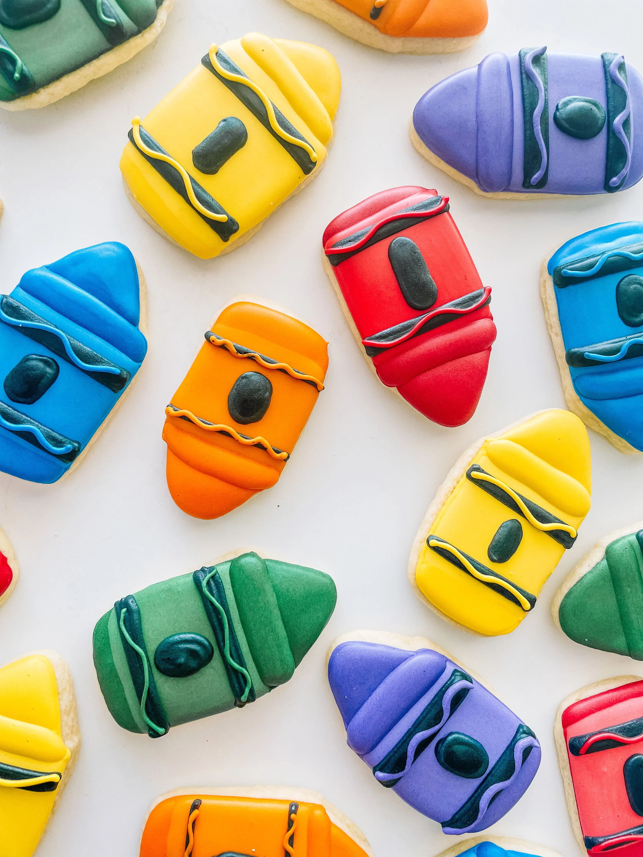 Colorful decorated cookies shaped like backpacks in yellow, red, blue, green, orange, purple, and teal on a white background.