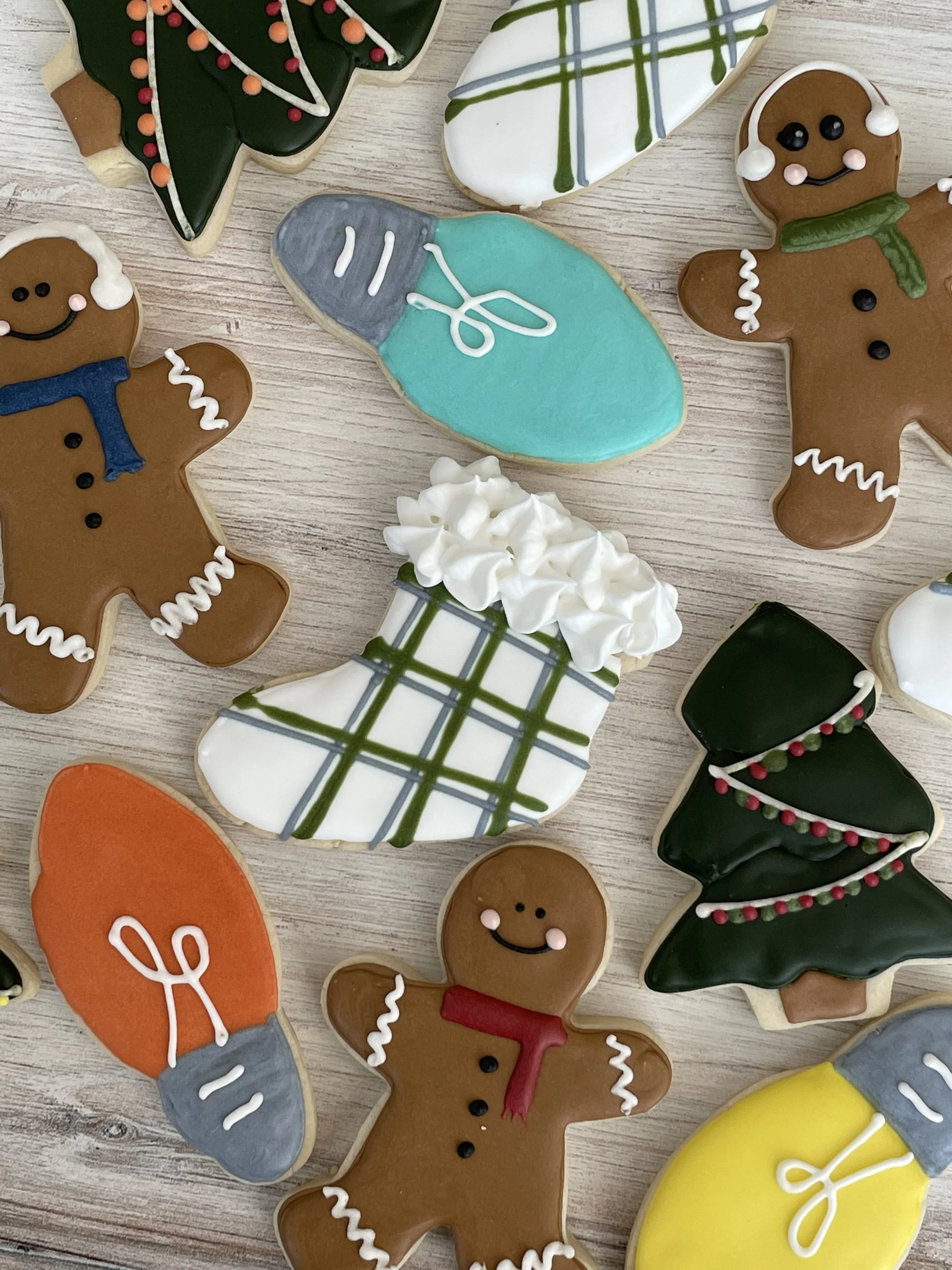 Decorated Christmas cookies shaped like gingerbread men, Christmas trees, and holiday-themed designs on a wooden surface.