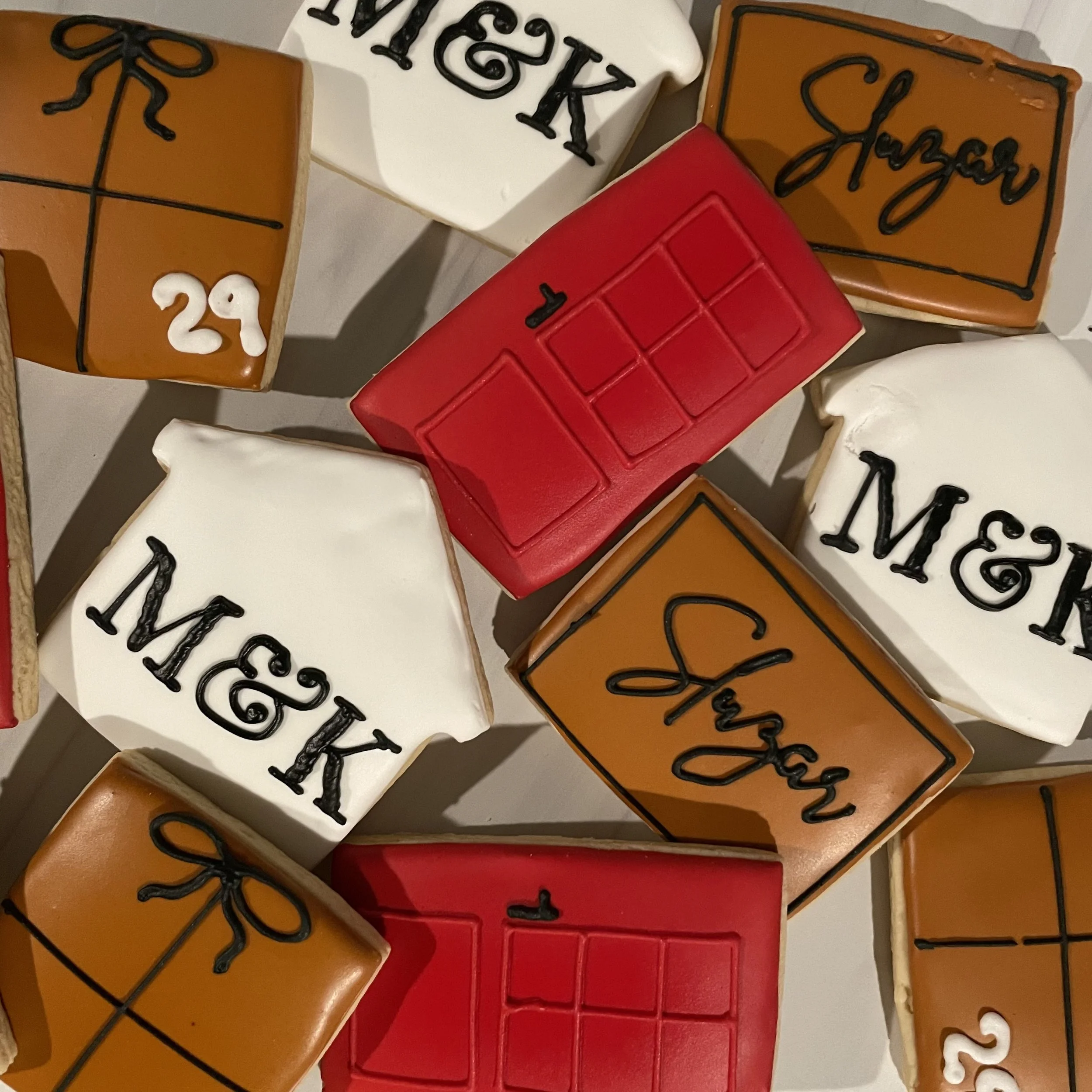 Decorated cookies in the shapes of presents, a Rubik's Cube, and letters spelling out 'Merry Christmas' and the date '12/25'.