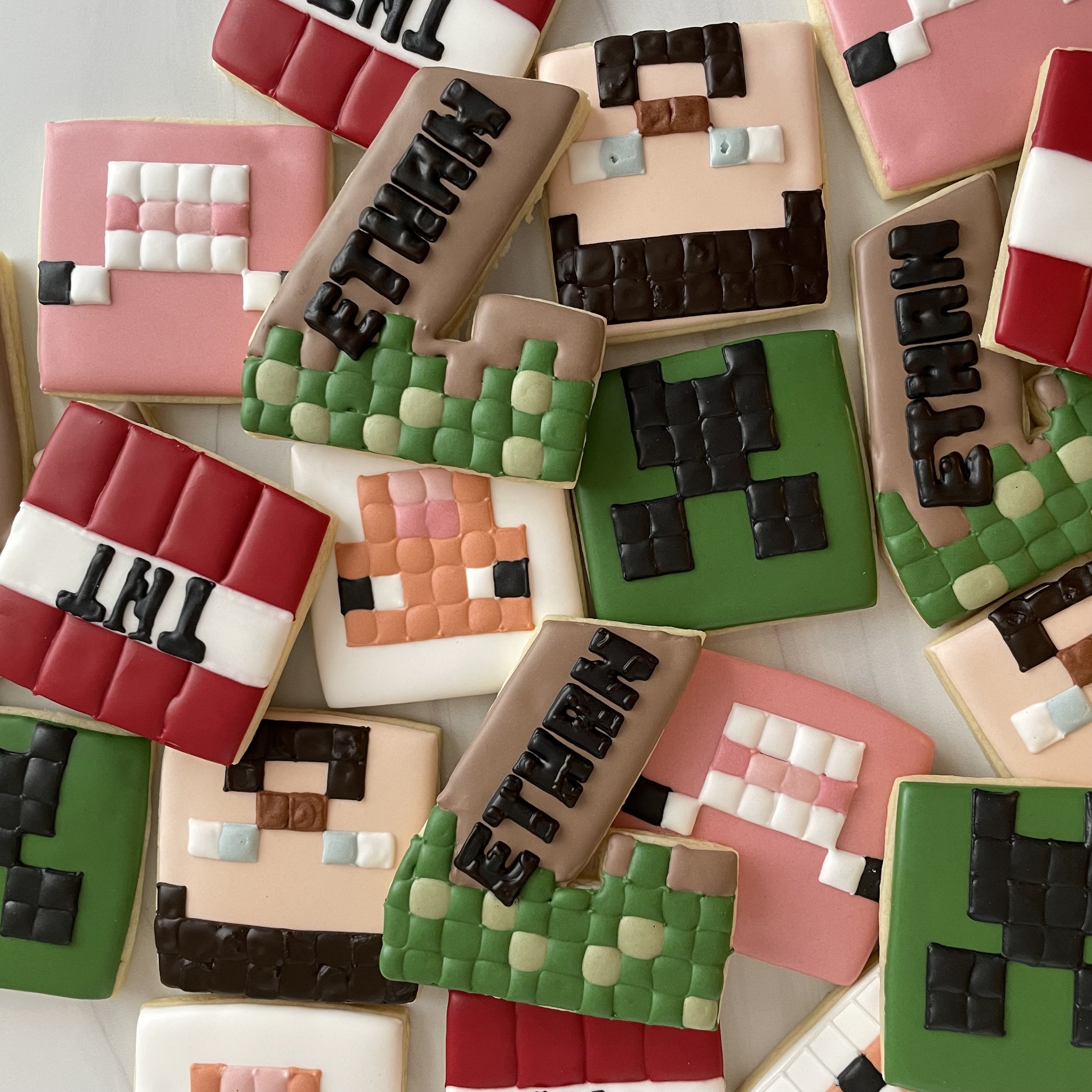 Assorted decorated cookies with various colors and designs, including block letters spelling 'LOVE' on some.