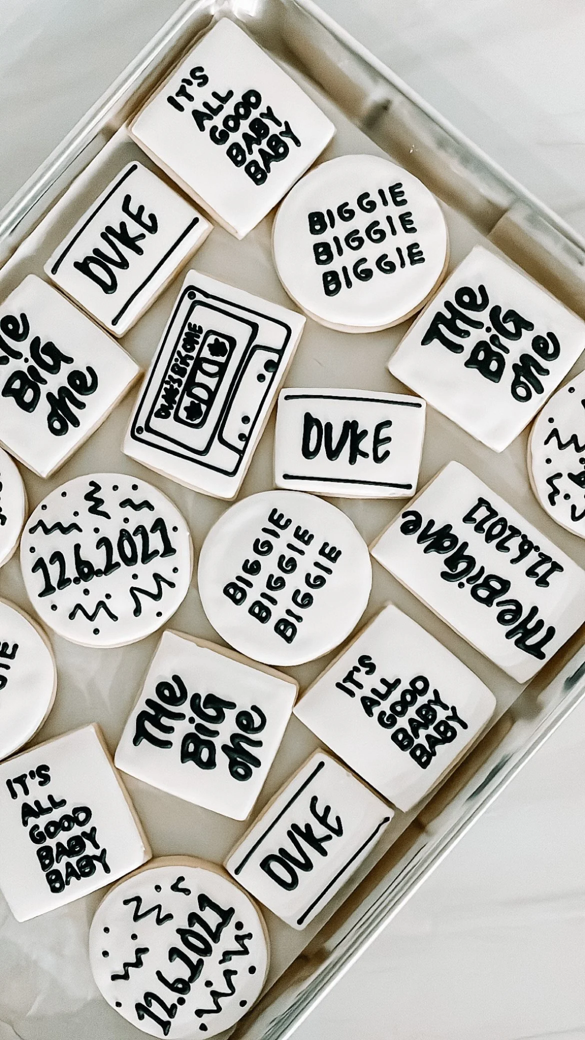 Assorted white candies with black handwritten text, including phrases like 'THE BIG ONE,' 'DUKE,' 'IT'S ALL GOOD BABY,' and the date '12.6.2021.'