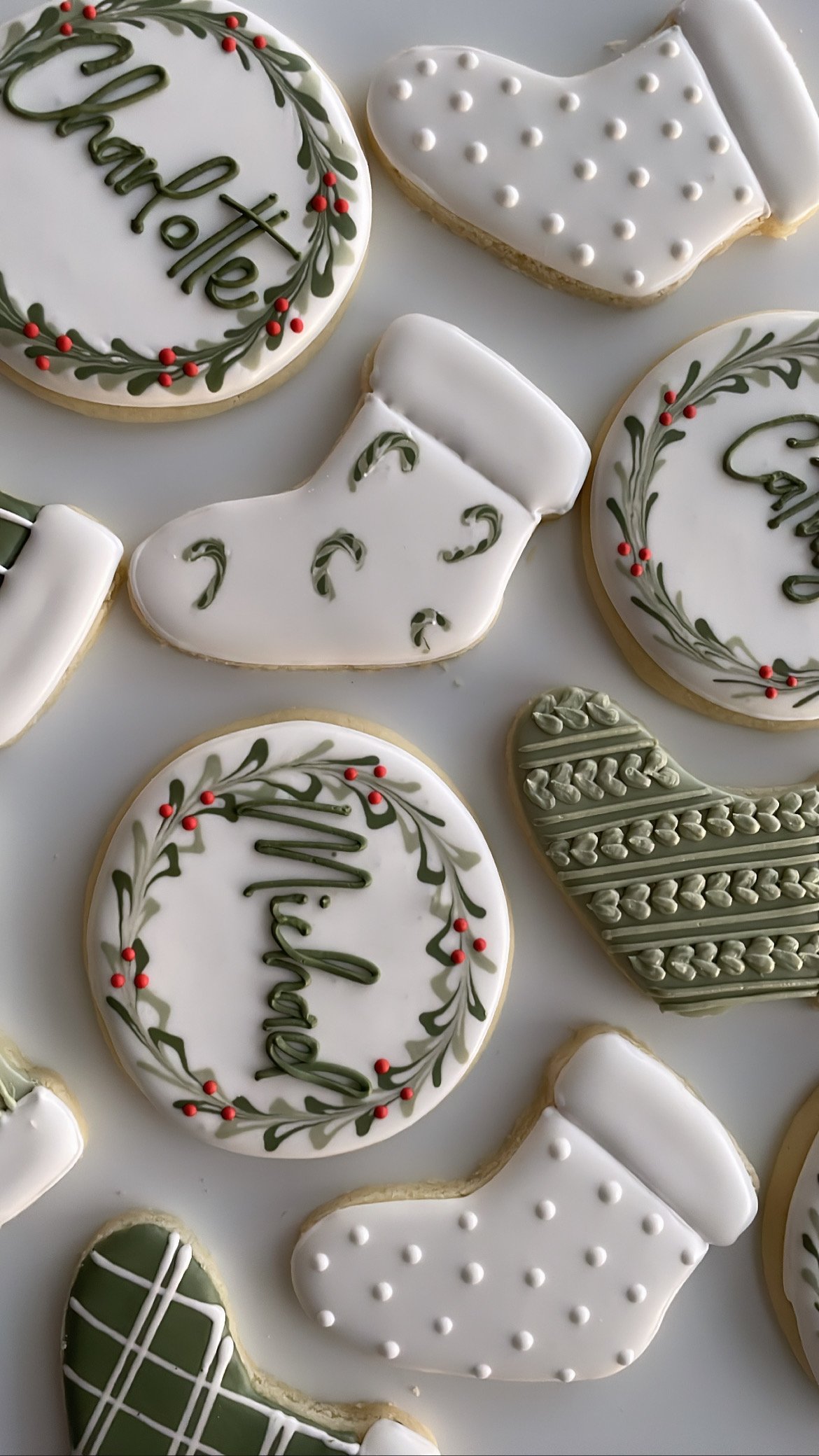 Assorted Christmas cookies decorated with white, green, and red icing, including cookies with the word "Christmas" and holiday wreath designs.