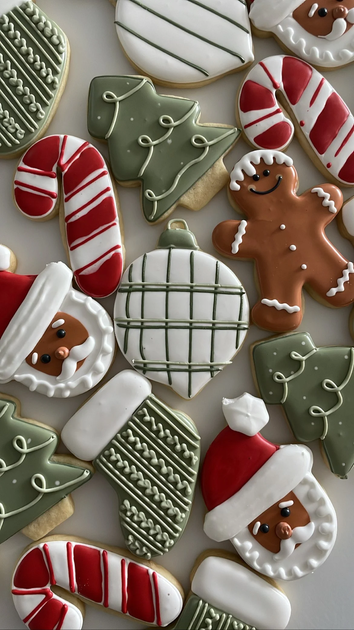 Decorated Christmas cookies shaped like Santa Claus, gingerbread men, Christmas trees, candy canes, and ornaments with festive icing and colors.