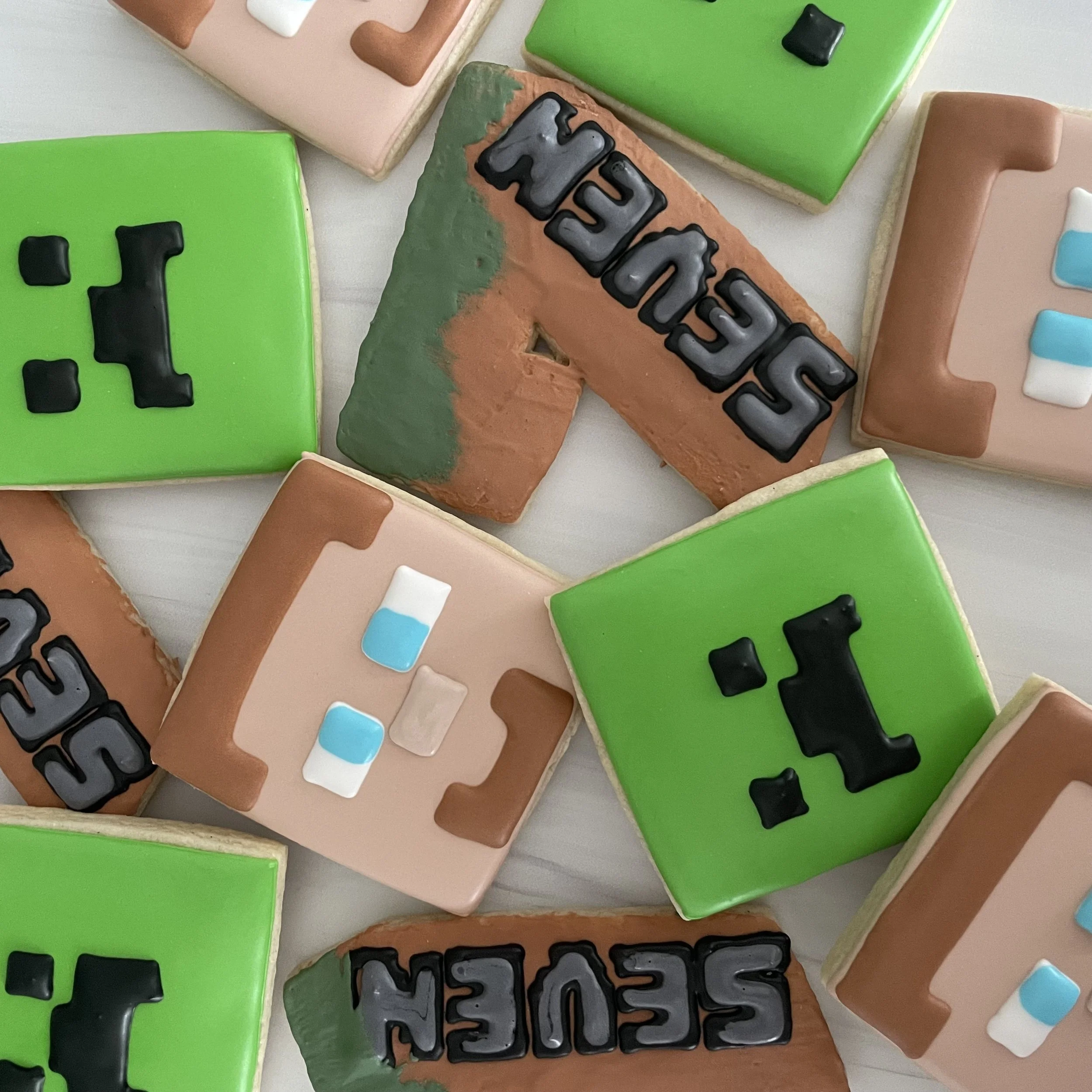 Close-up of decorated sugar cookies with letters and colorful icing, some spelling out the word 'HELP'.