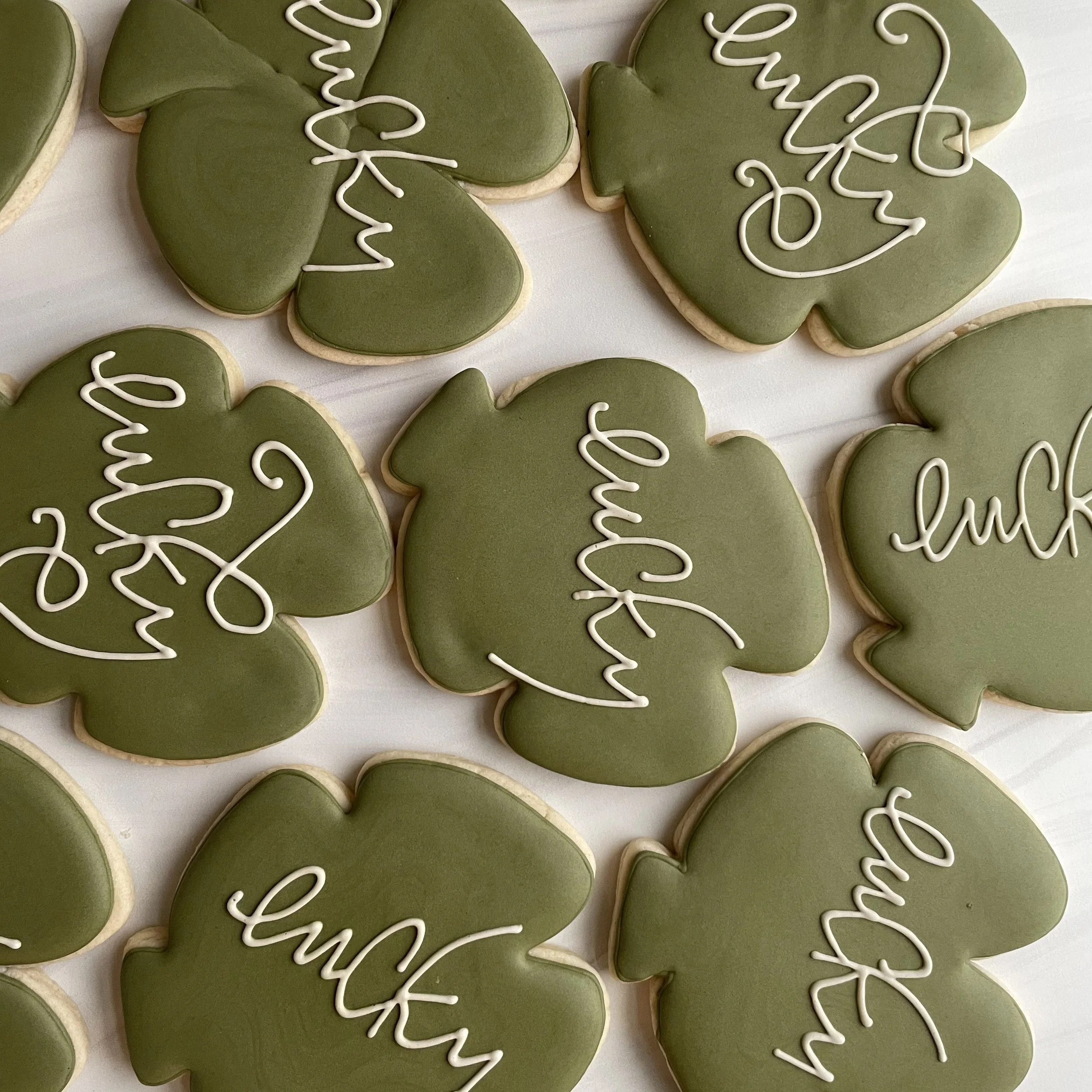 Green leaf-shaped cookies with white icing that says "Thank you" on some.