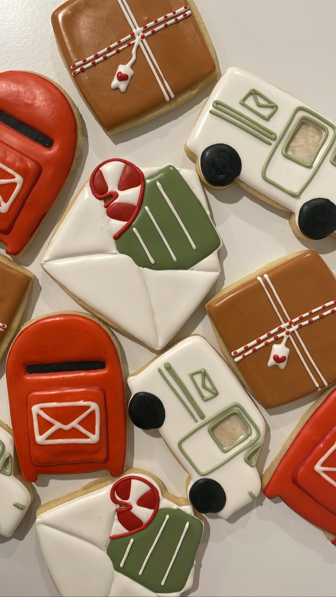 Decorated sugar cookies shaped and decorated like Christmas-themed items including a mitten, gift box, Christmas card, and mailbox, with icing in red, green, white, and black colors.