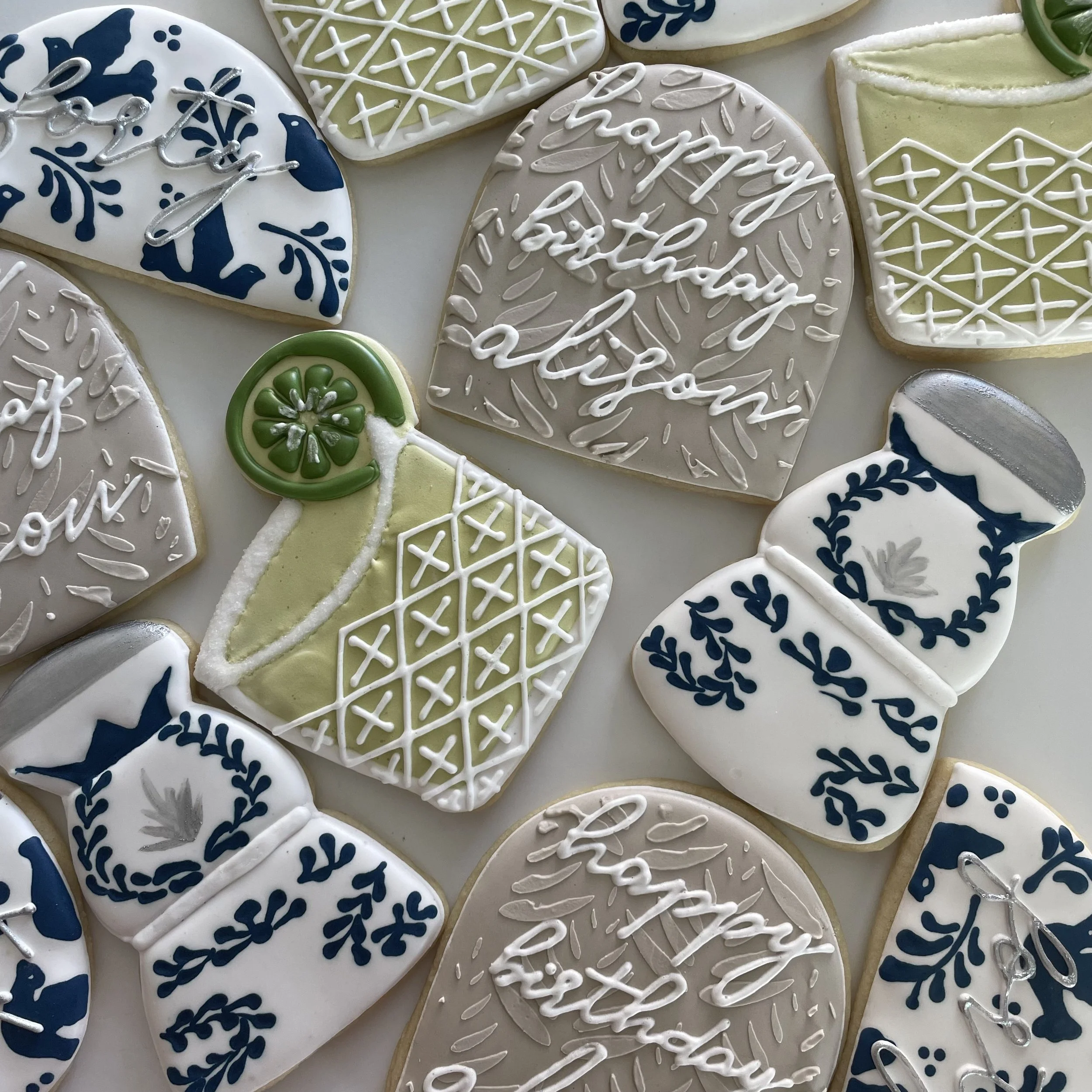 Assorted decorated Christmas cookies, including hearts with white, green, and blue icing, some with snowflake patterns and message writing, arranged on a flat surface.