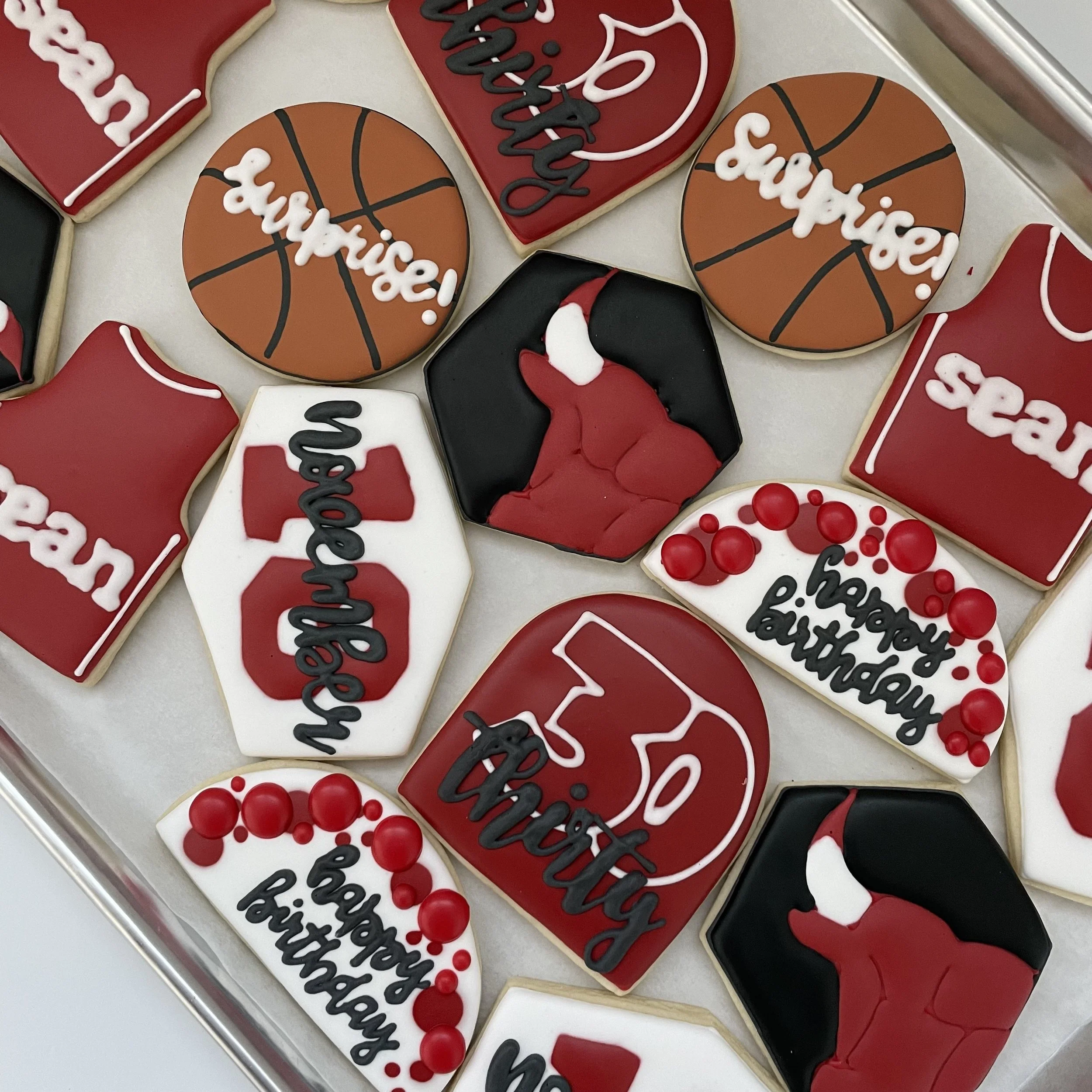 Decorated cookies with basketball themes and phrases celebrating a birthday, featuring red, black, white, and orange icing.