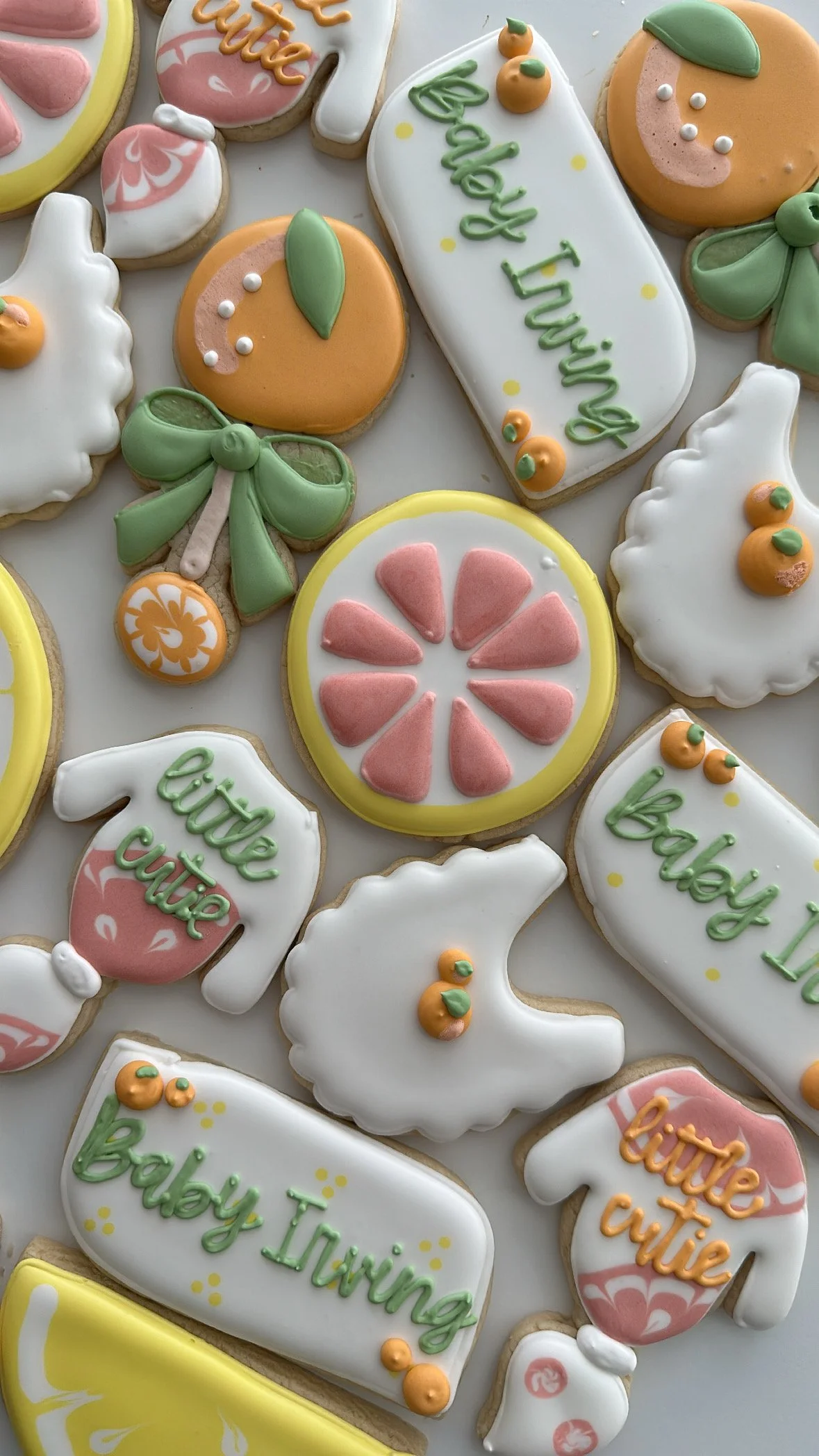 Decorated cookies with baby shower themes including text such as 'Baby Shower' and 'Baby Towing', fruit designs, bows, and pink and green pastel decorations.
