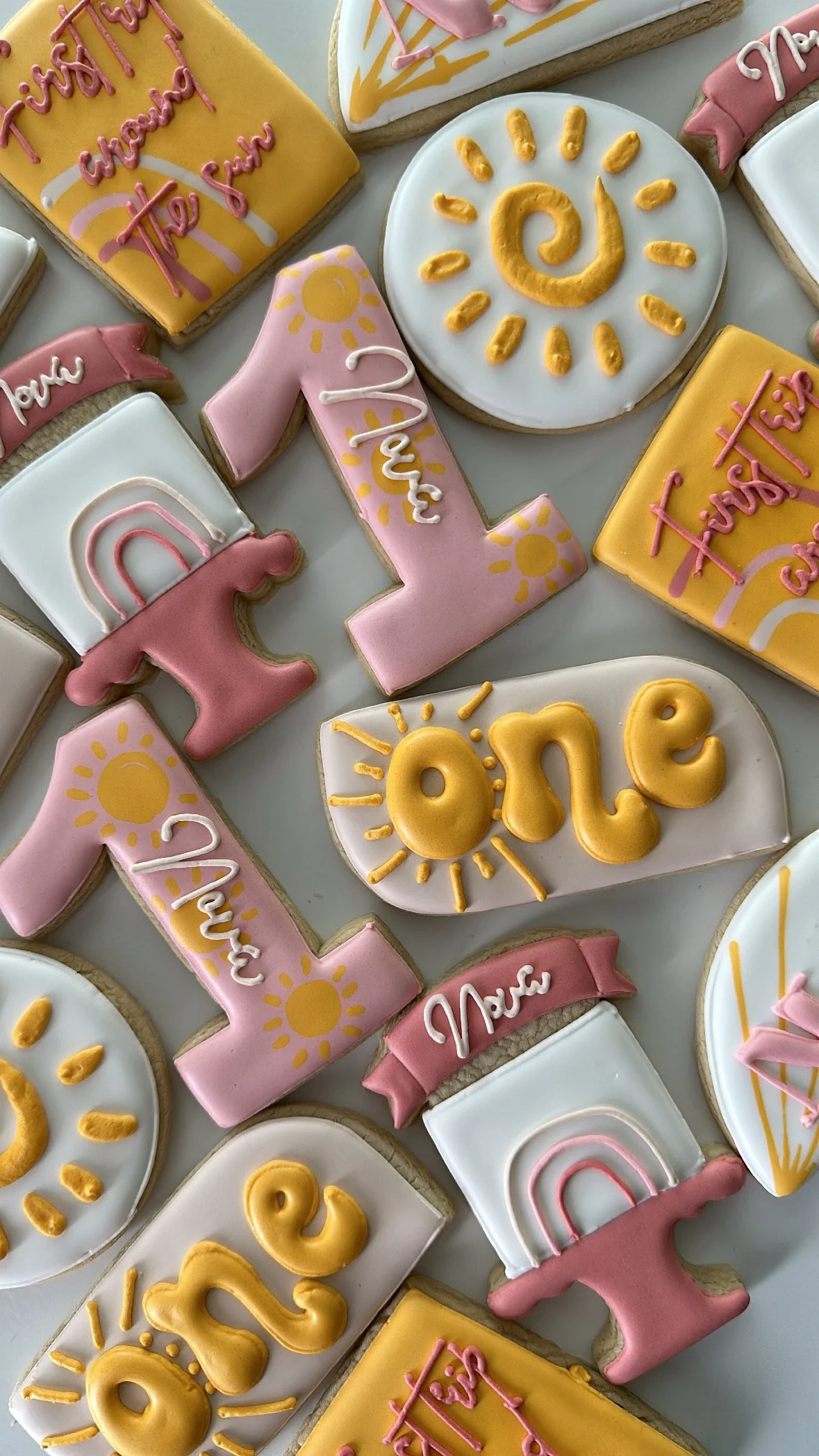 Decorative cookies with colorful icing, including words like 'Love,' 'Thank You,' and 'Have a Good Day,' along with sun and rainbow motifs.