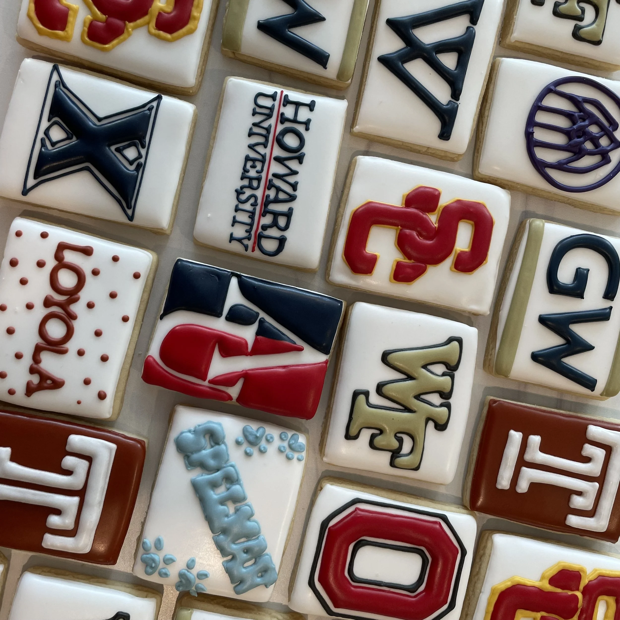 A collection of decorated sugar cookies with various designs and colors, including holiday themes, geometric patterns, and text.