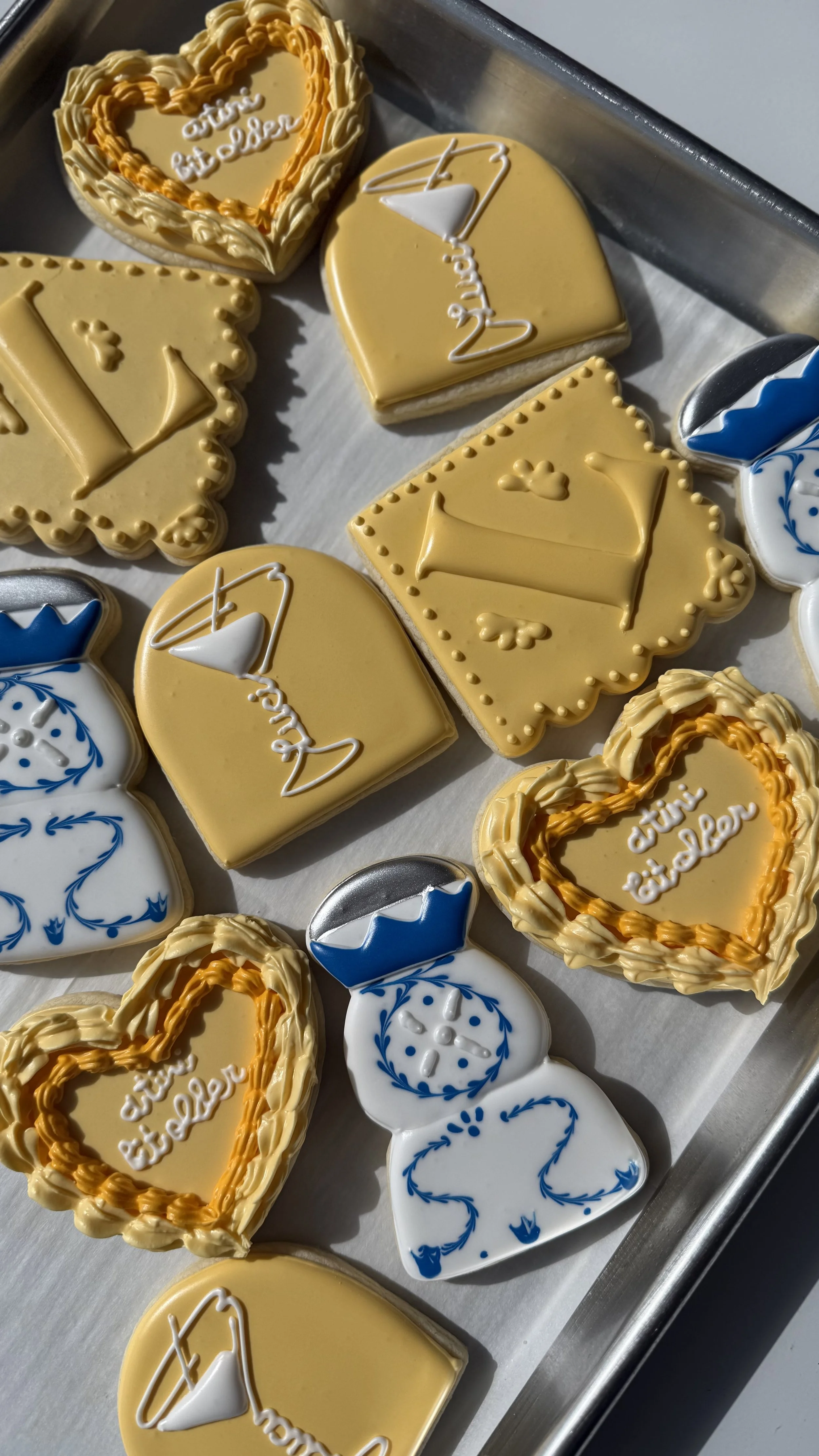 Decorative cookies with yellow, white, and blue icing, some with 'happy birthday' messages and heart or snowflake designs.