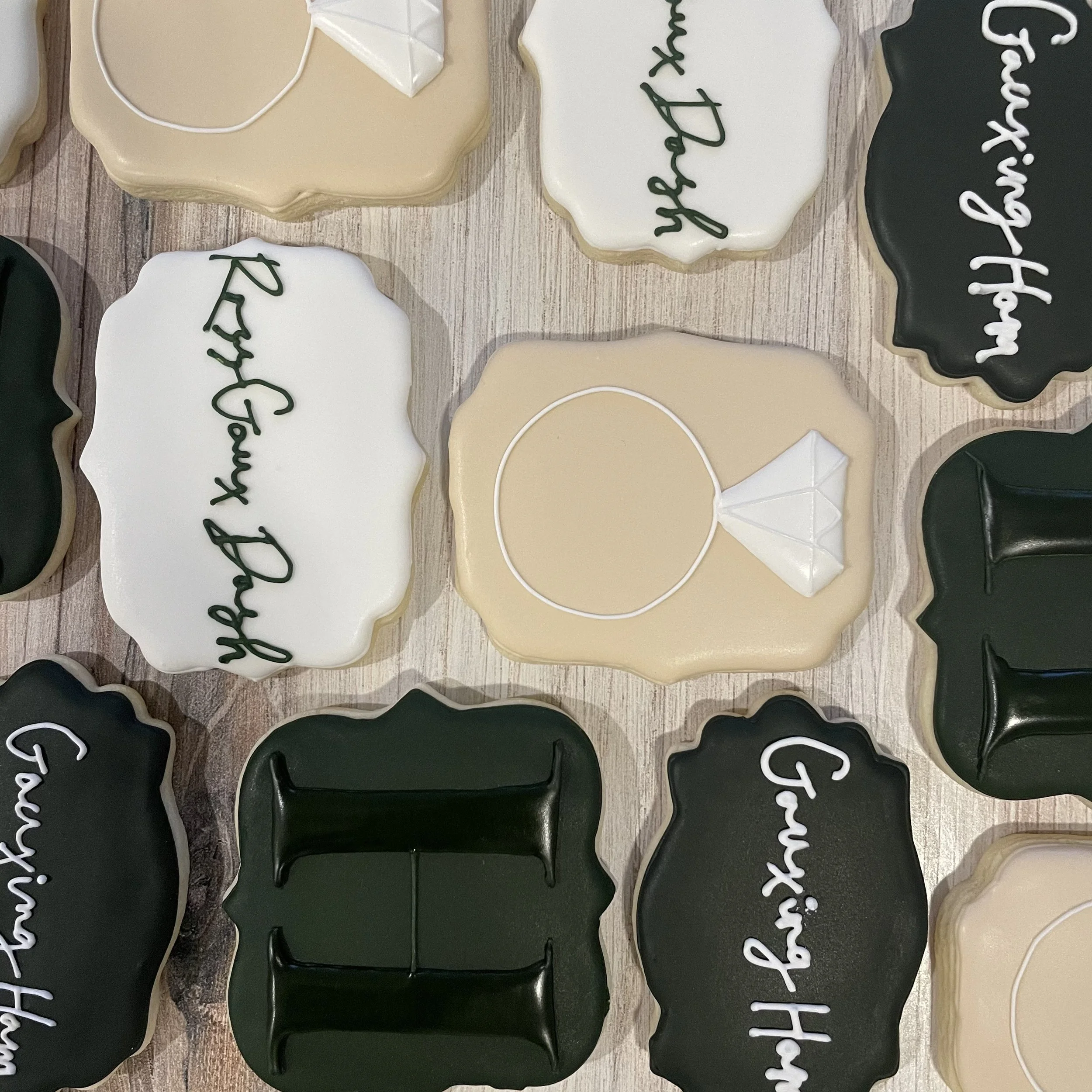 Decorated cookies with black, white, and beige icing, with messages like 'Happy Valentine's Day' and 'You're my happiness' written on them, displayed on a wooden surface.