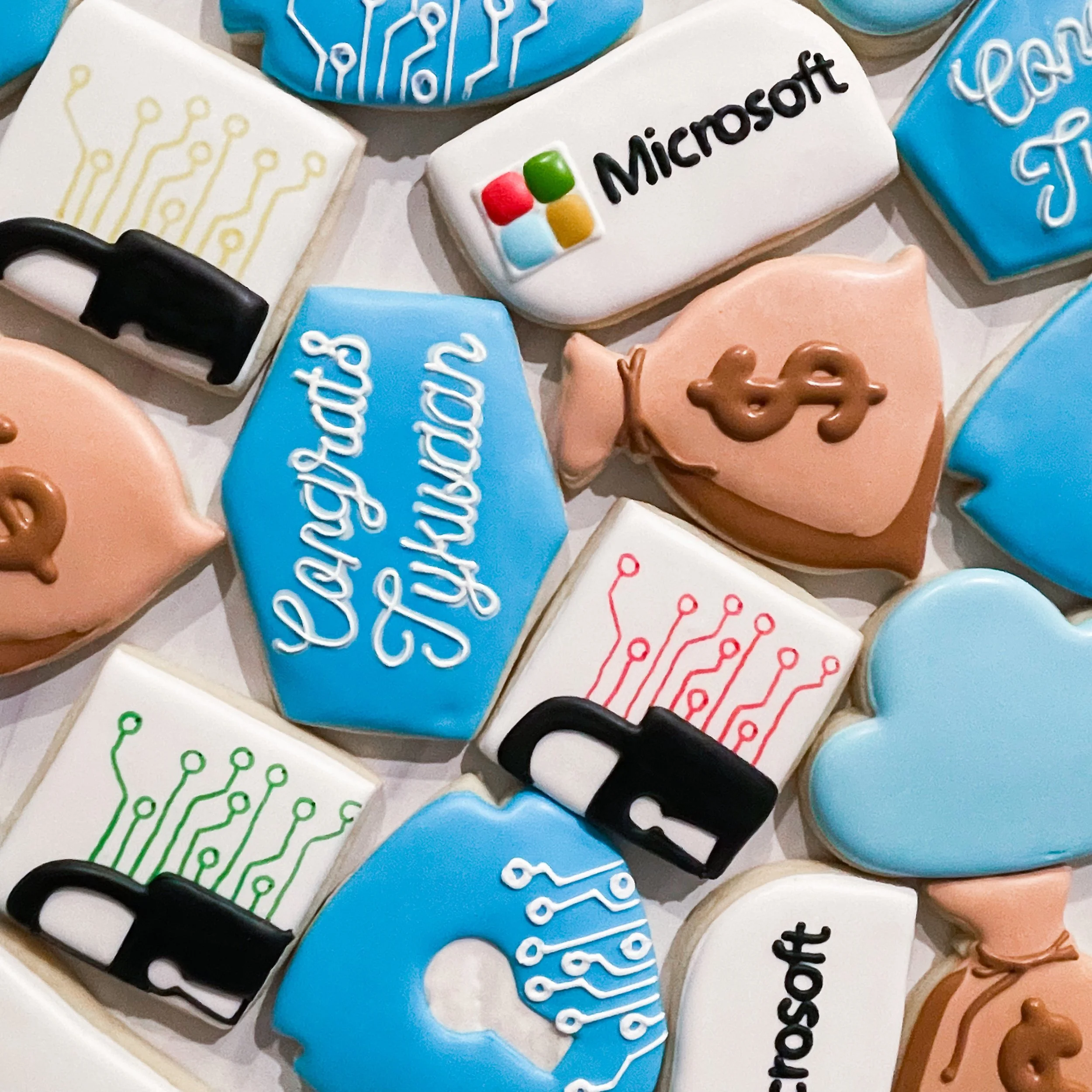 Decorated cookies with technology themes, including one with the Microsoft logo, circuit patterns, and related phrases.