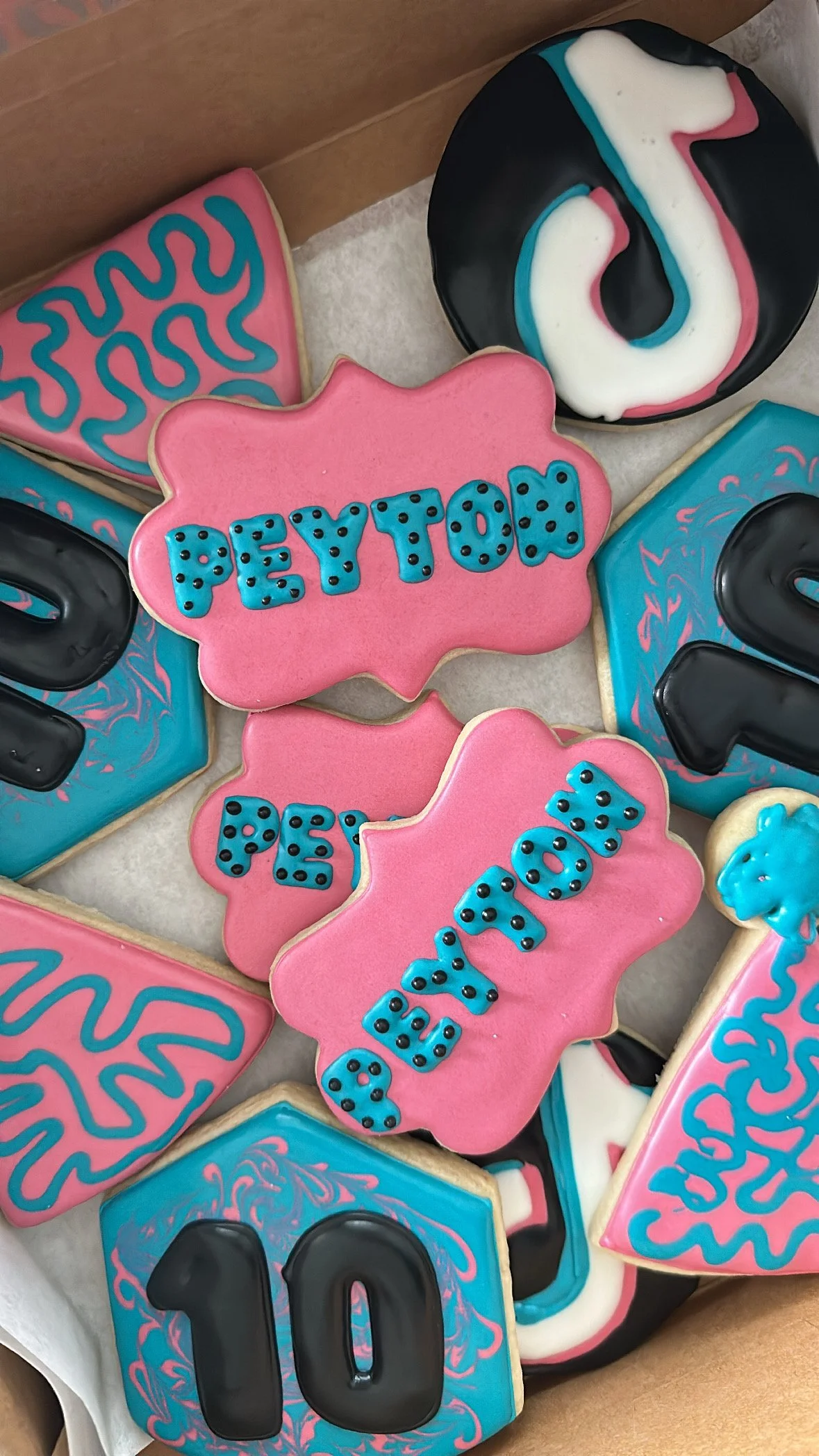 Celebratory cookies with pink, blue, black, and white icing, some with the number '2023' and 'PetToy' written on them.