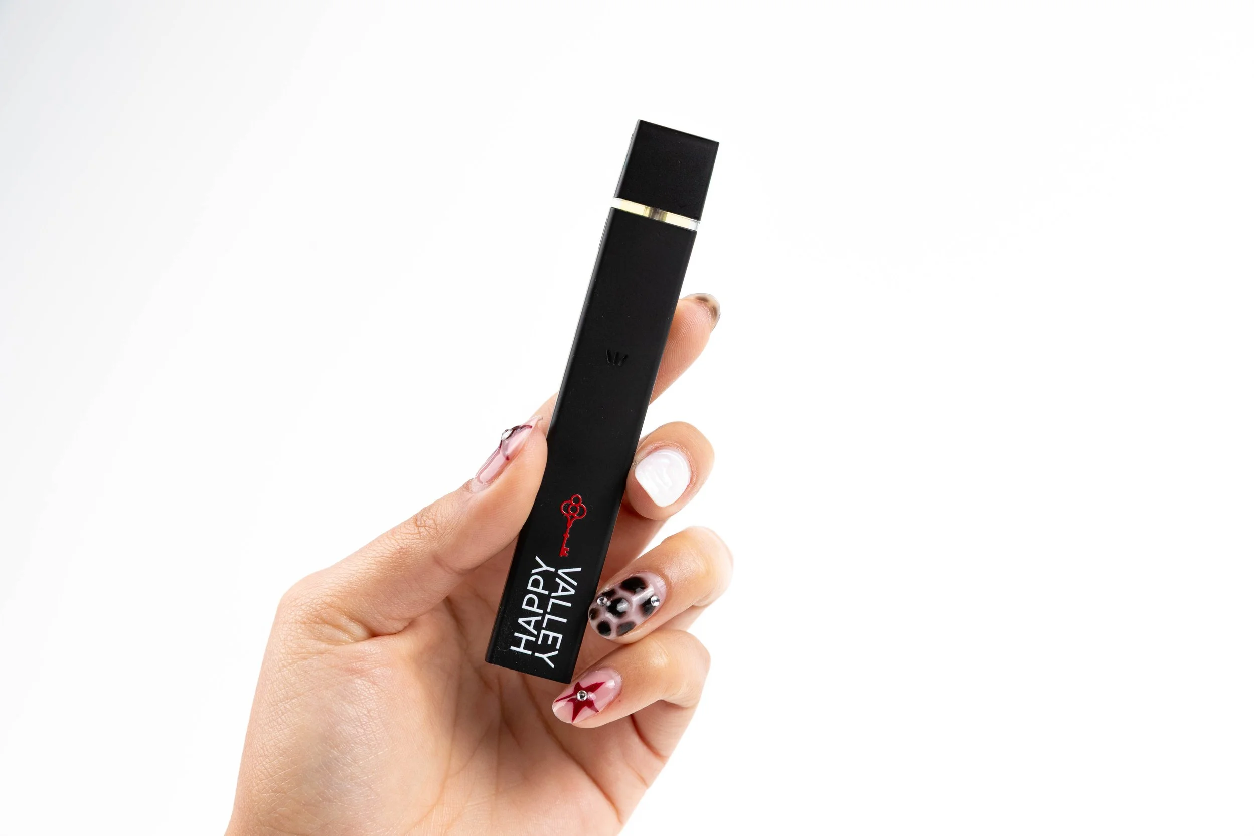 Hand holding a black lipstick tube with holiday-themed nail art.