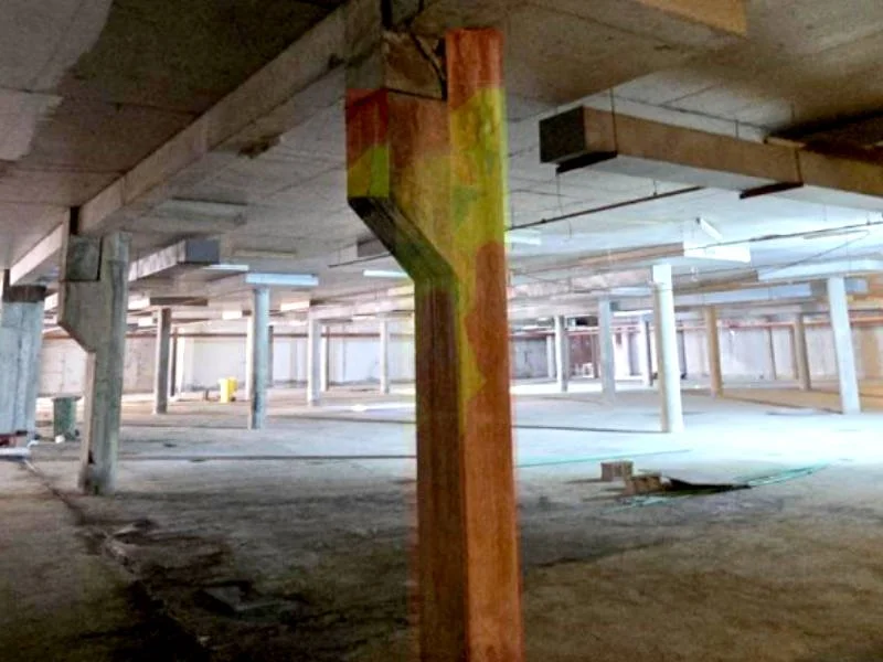 Construction site showing concrete support beams and wooden columns, with corrosion potential map overlay of red, orange, and yellow spots.