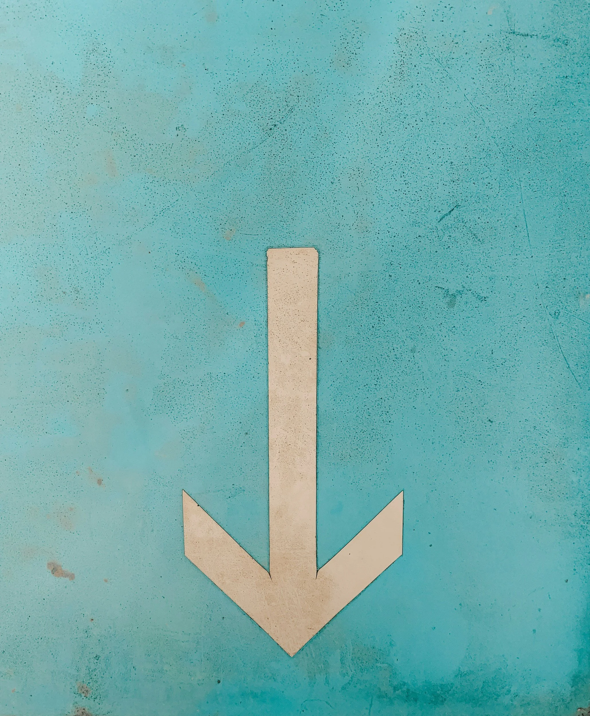 A white geometric arrow pointing downward on a textured turquoise background.