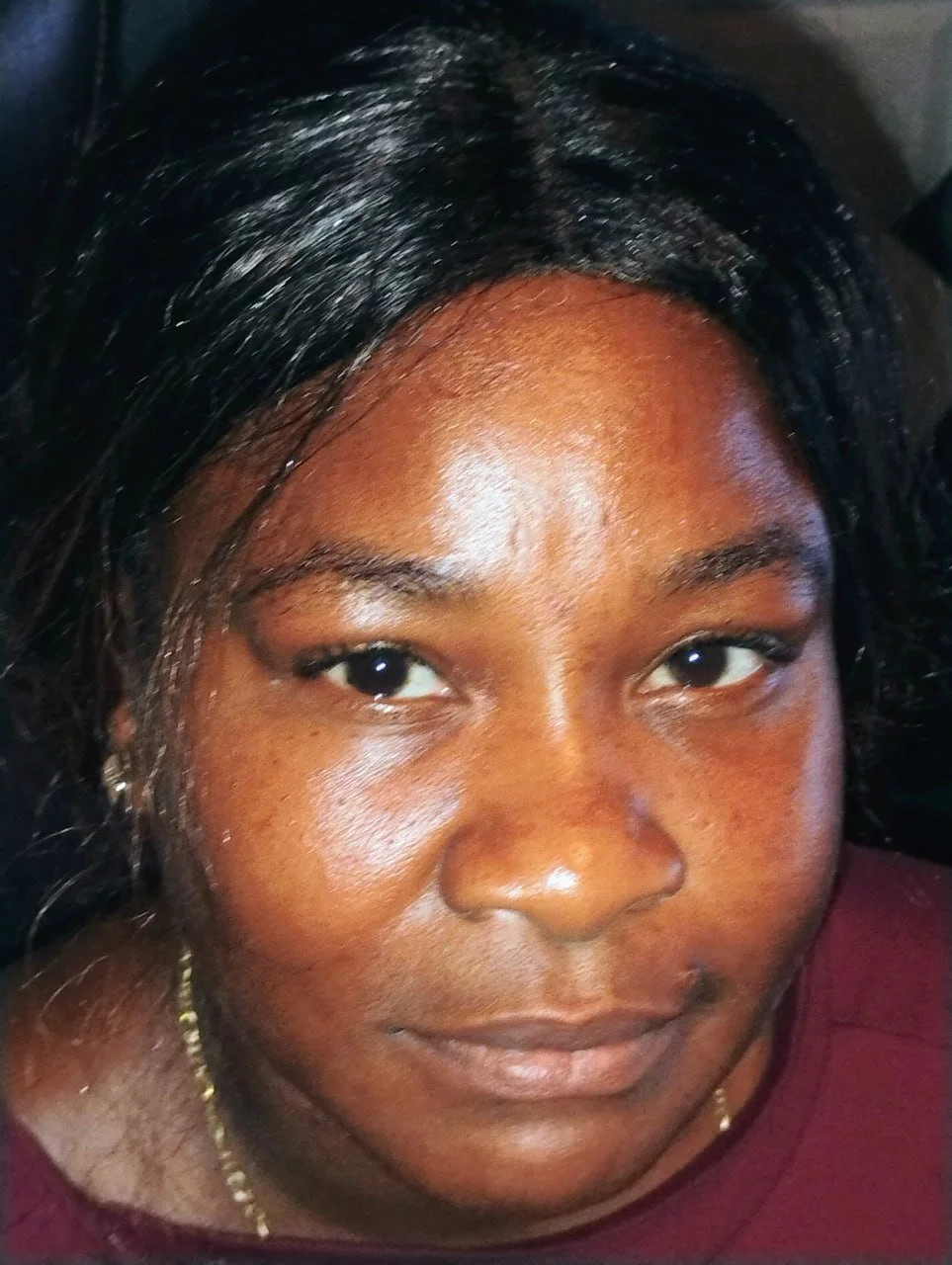 Close-up of a woman with dark hair and brown skin, smiling softly.