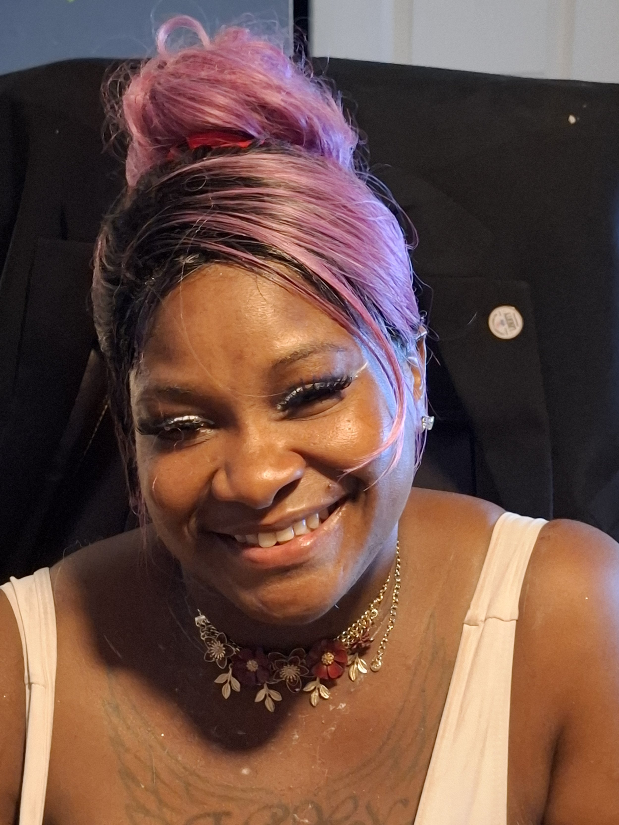 Close-up of a woman with dark hair and brown skin, smiling softly.
