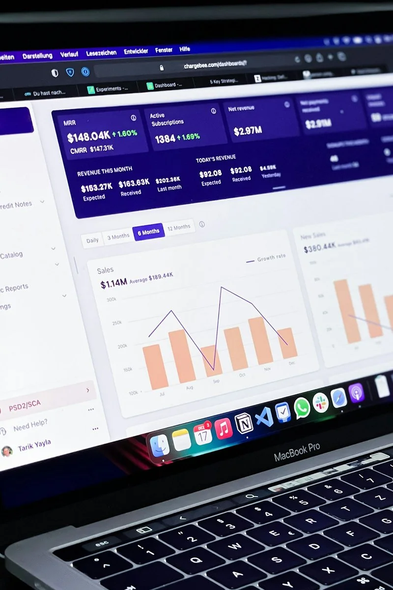 Laptop screen displaying a business analytics dashboard with revenue figures, active subscriptions, sales charts, and navigation tabs.