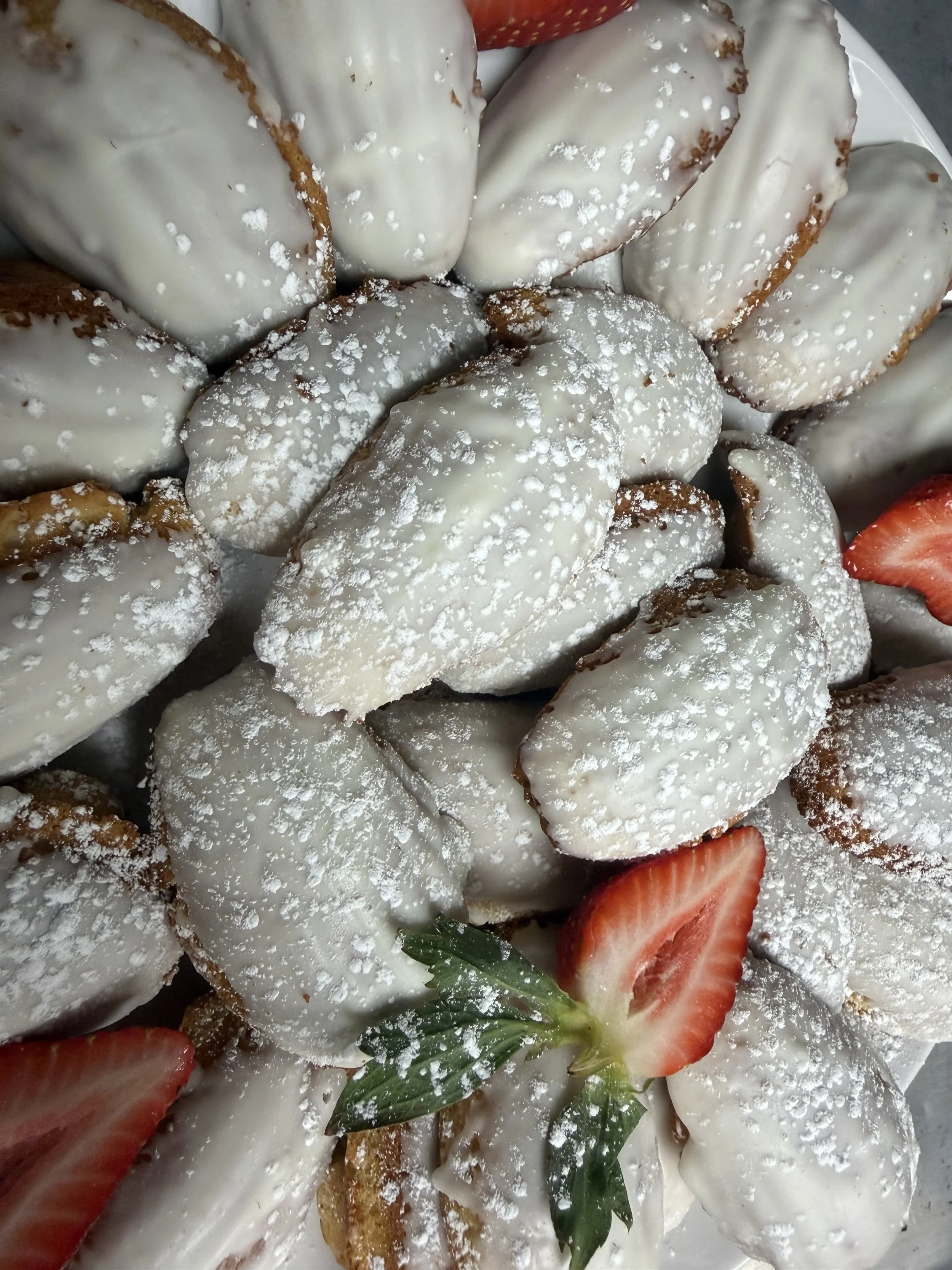 Close-up of strawberries dipped in white chocolate, sprinkled with powdered sugar.