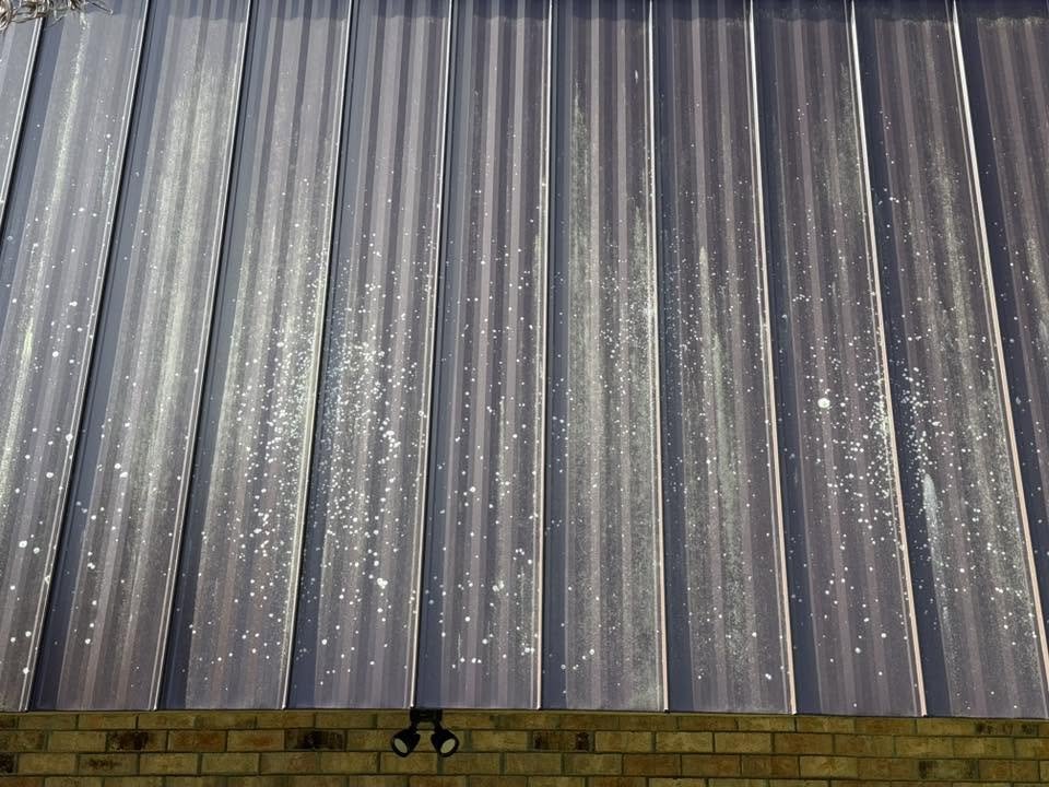 Close-up photograph of a metal rooftop with raindrops on it.