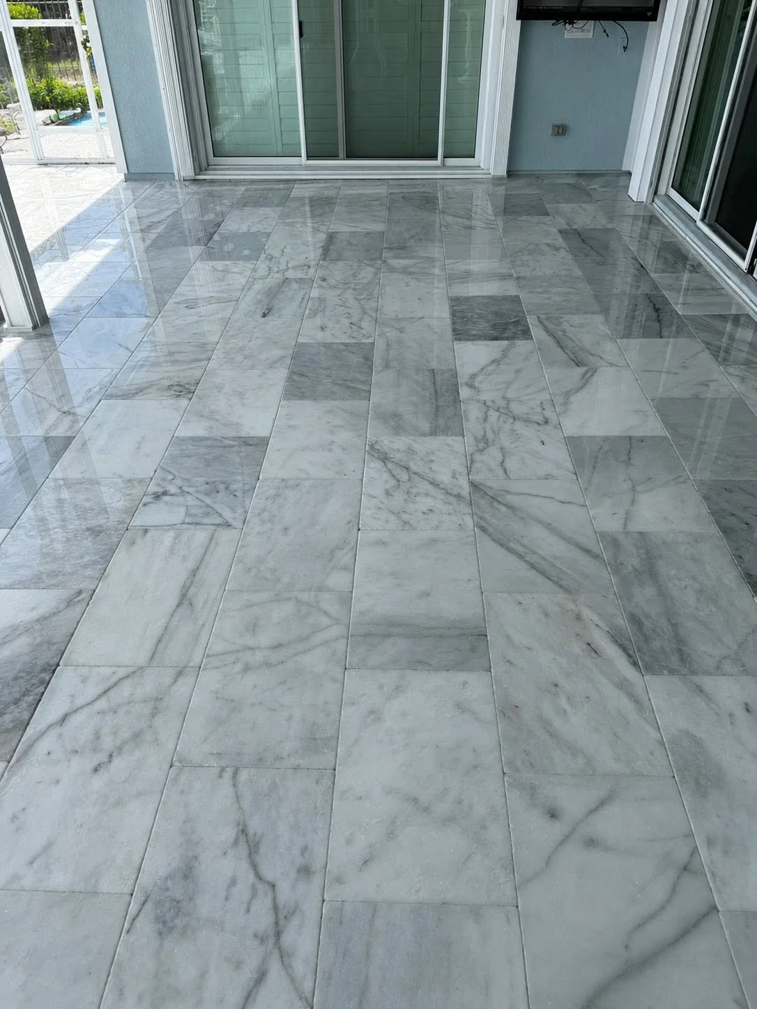 Indoor patio with polished marble tile flooring and sliding glass doors leading outside.