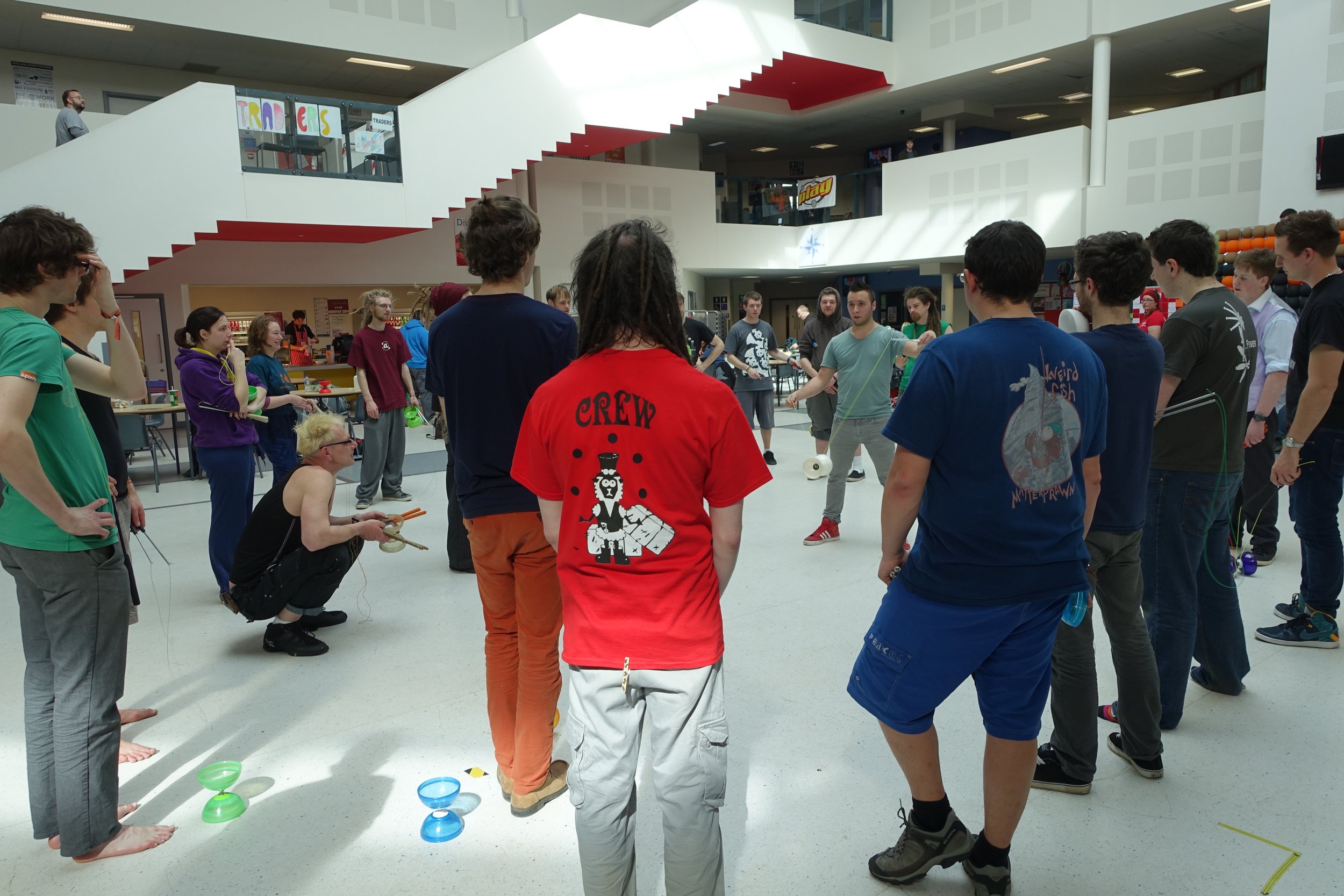 Groupe de jeunes adultes jouant à un jeu de yoyo dans un espace intérieur spacieux.
