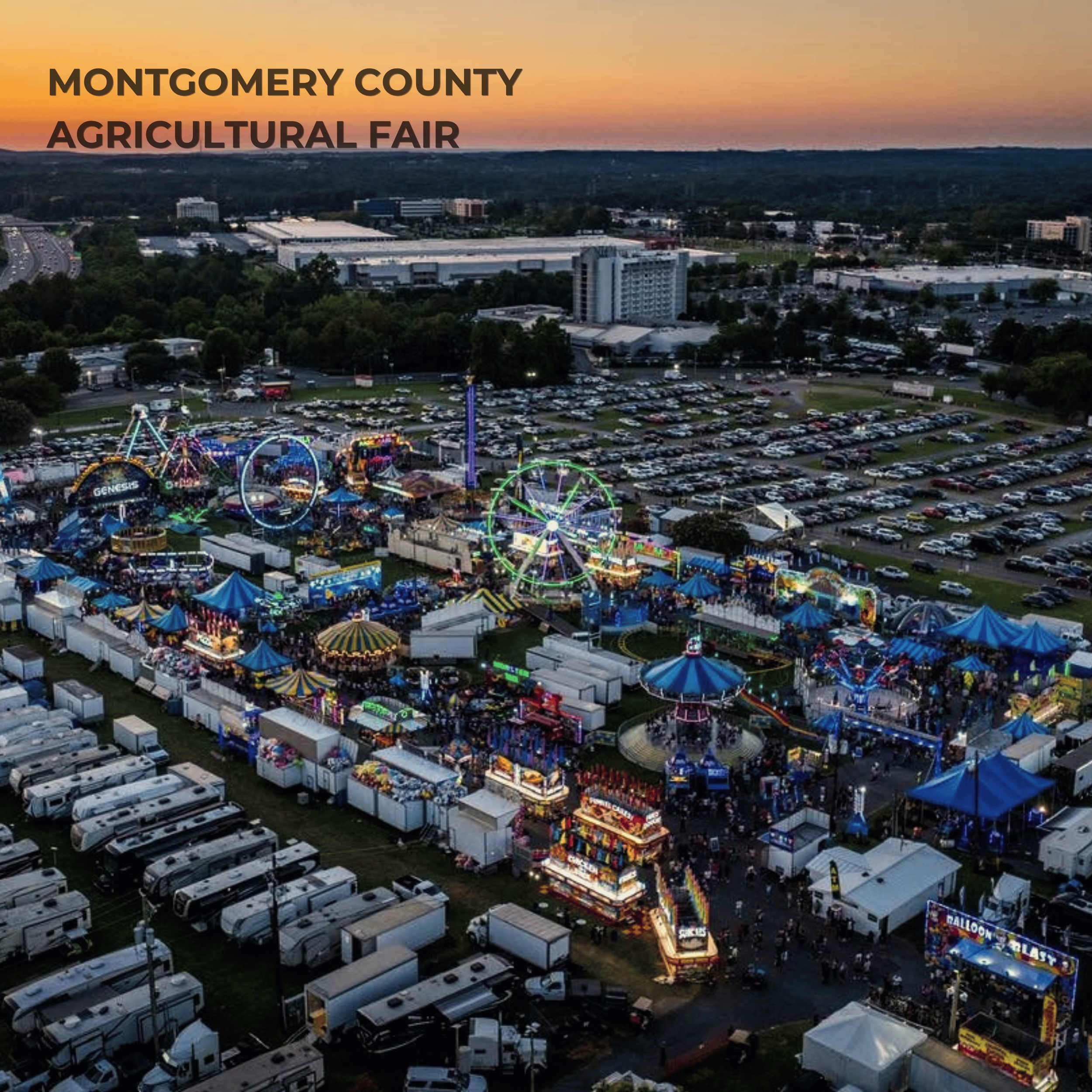 An aerial view of the Montgomery County Agricultural Fair with bright carnival rides, booths, and a large parking lot, set against a backdrop of buildings and hills at sunset.