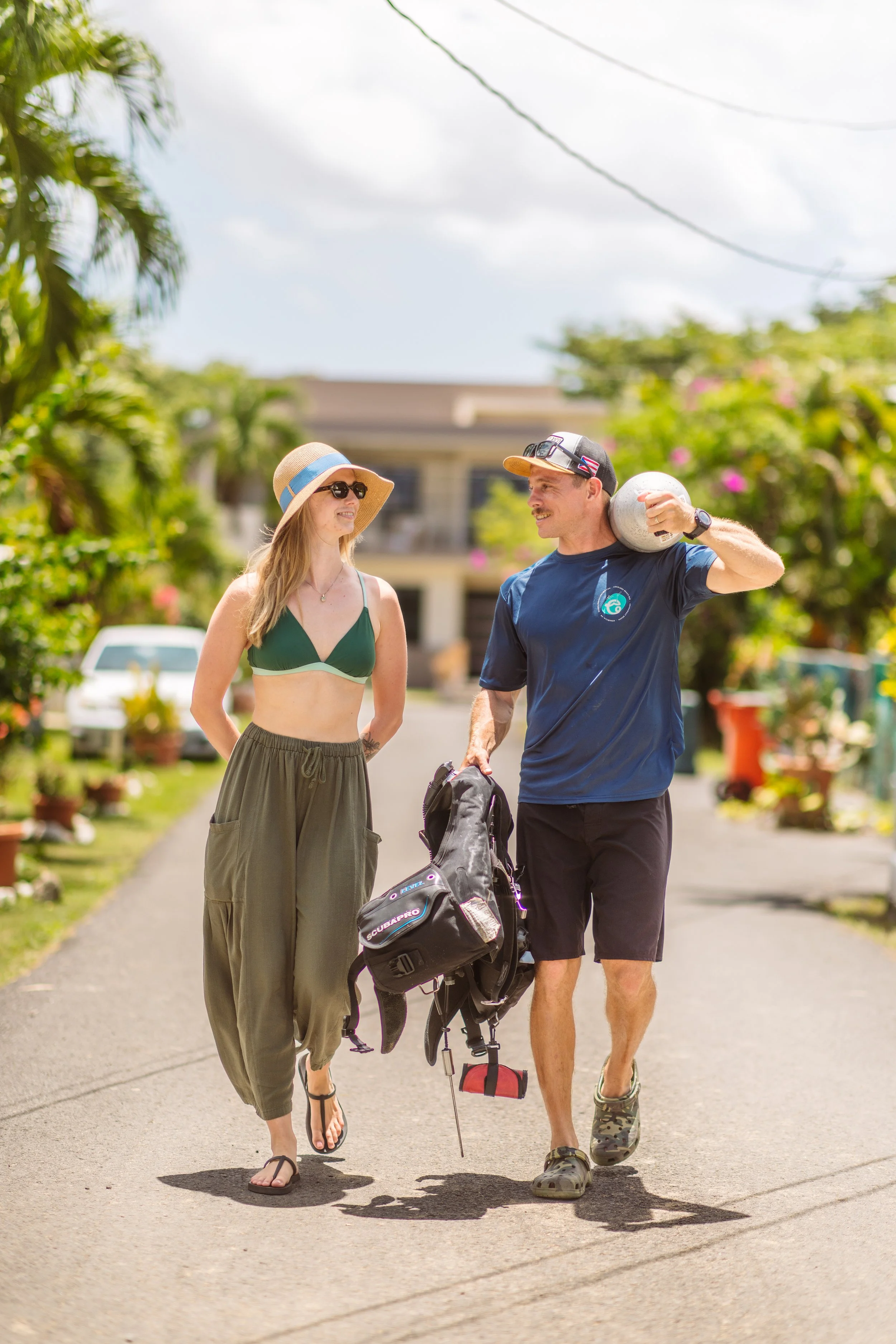 A Vantage Dive Club instructor carrying a scuba tank for a guest, showcasing our valet gear service in Rincón, Puerto Rico.
