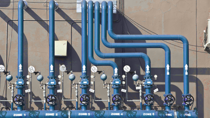 Several large blue pipes with valves connected in an industrial setting, labeled with zones and FHC.