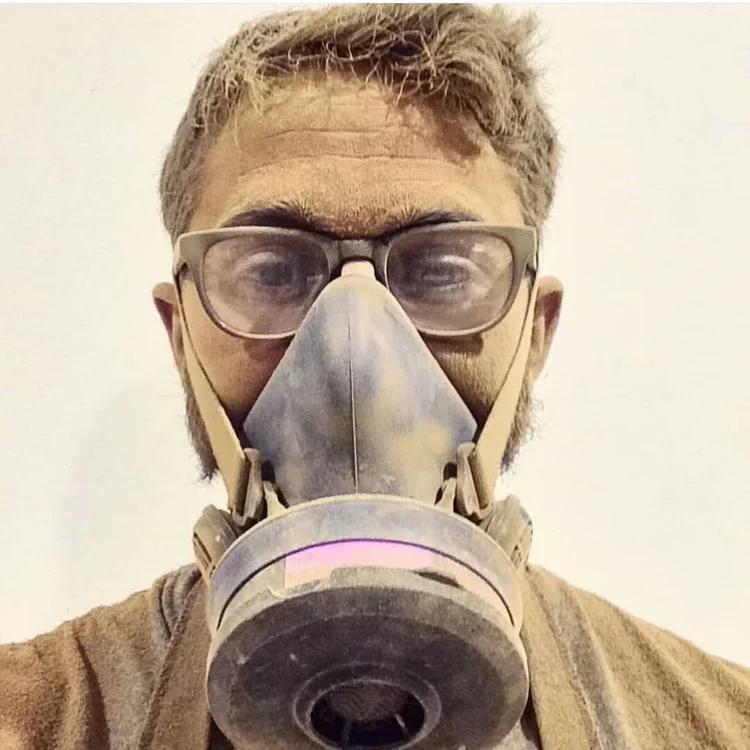 A person with glasses wearing a protective mask and respirator taking a selfie.