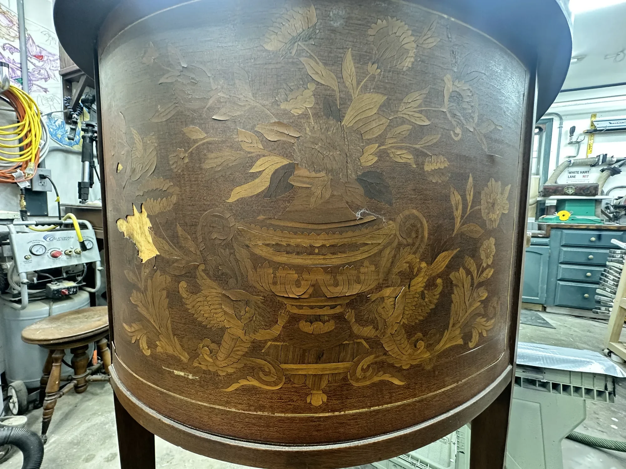 Dutch demilune desk before restoration, with lifted and missing marquetry veneer in a floral urn and griffin design