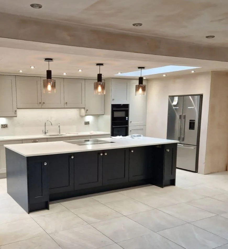Modern kitchen with a black island, white cabinetry, stainless steel refrigerator, and hanging pendant lights.