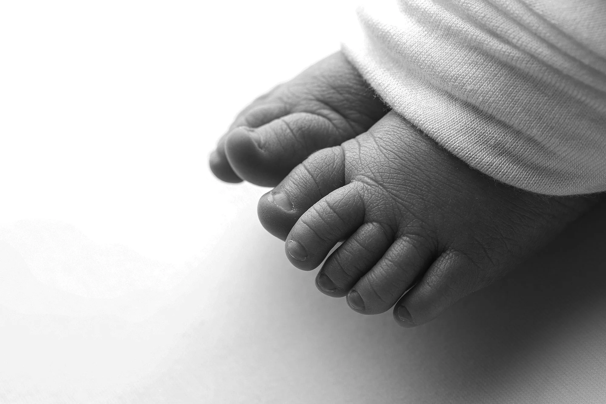 Close-up of two black hands clasped together, with the sleeve of a light-colored shirt visible on the person at the top, against a plain white background.