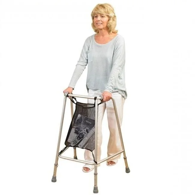 A woman with blonde hair in a light long-sleeve shirt and white pants standing with a walker that has a built-in pouch.