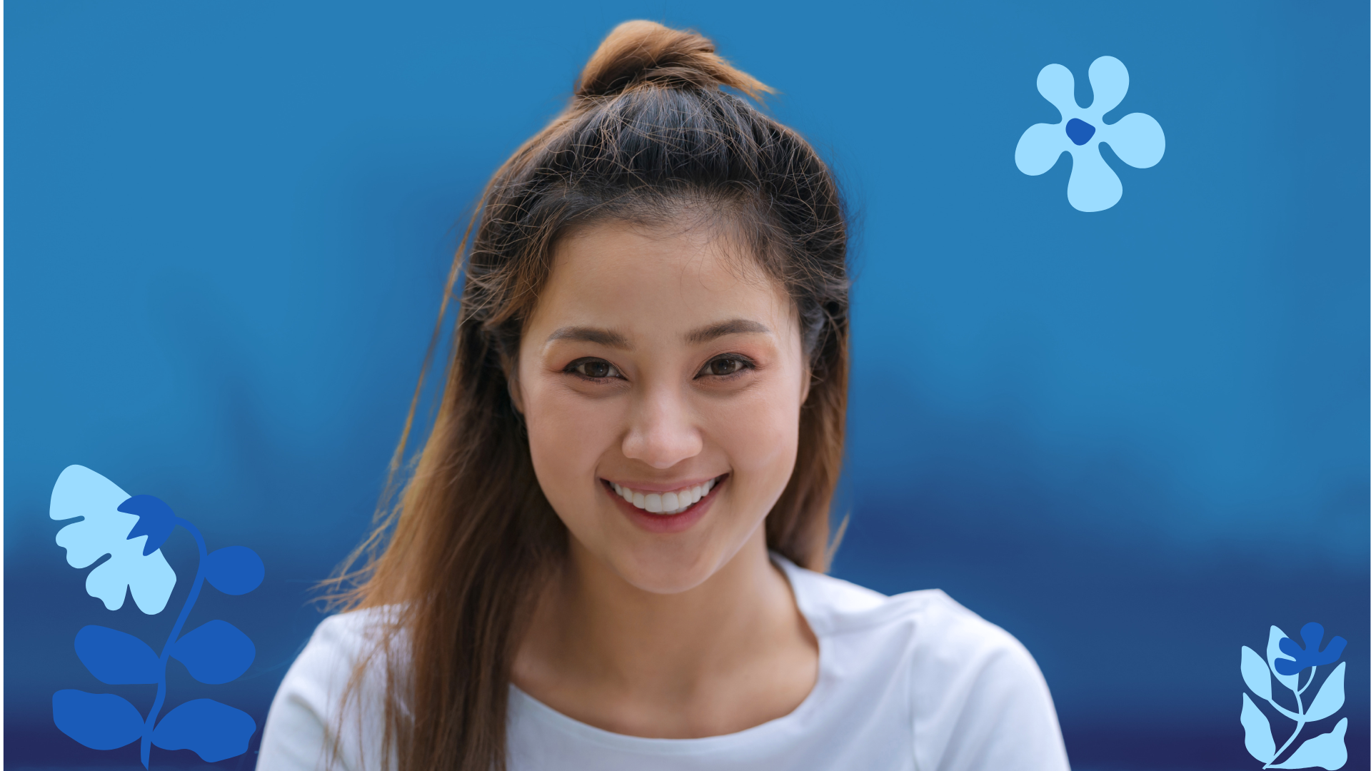 A smiling woman with brown hair tied in a bun, wearing a white top, standing in front of a blue background with stylized blue flower illustrations.