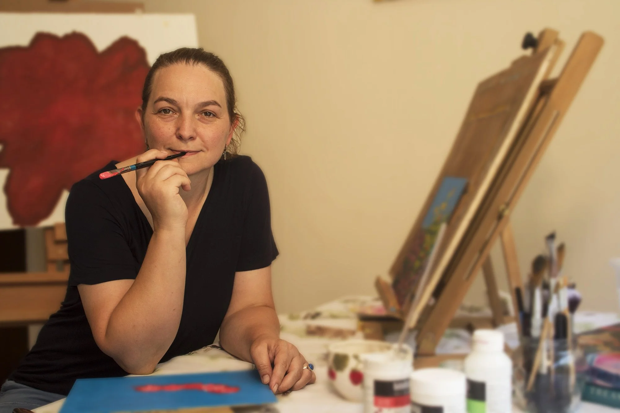 Artist painting in a Dorset studio with brushes and canvas, showing the handmade process behind each original artwork