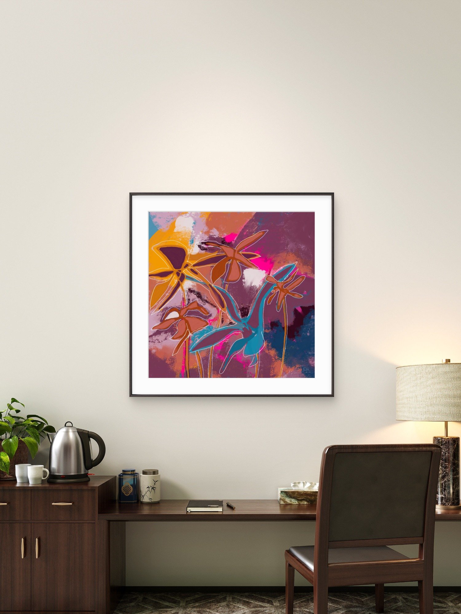 'The Best of Both Worlds,' abstract bright botanical painting by Emily Whitish, hangs in a hotel room above a wooden desk with a black notebook, a lamp with a beige shade, a kettle, mugs, and a dark wooden chair.