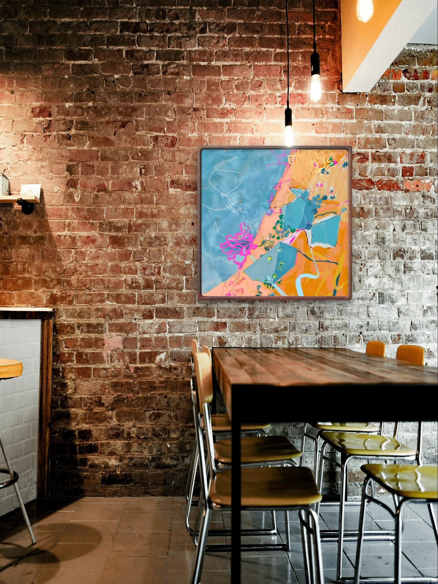 Interior of a cafe with a red brick wall, a framed colorful abstract painting by Emily Whitish, called 'Rise to the Occasion,' a wooden table, and yellow chairs.