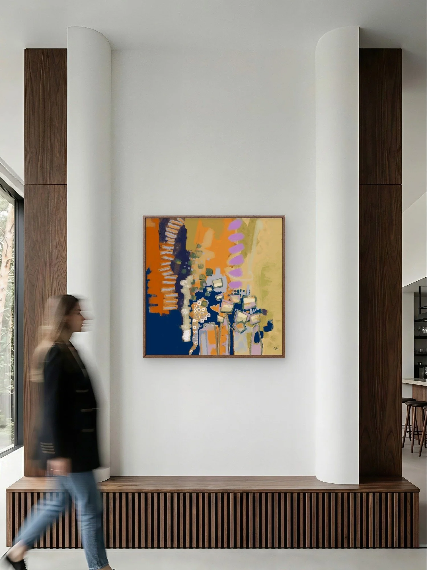 Interior of a modern building featuring a colorful abstract painting by Emily Whitish called 'Hit a Nerve,' on a white gallery wall flanked by dark wood panels. A woman dressed in black and blue jeans, is walking past.