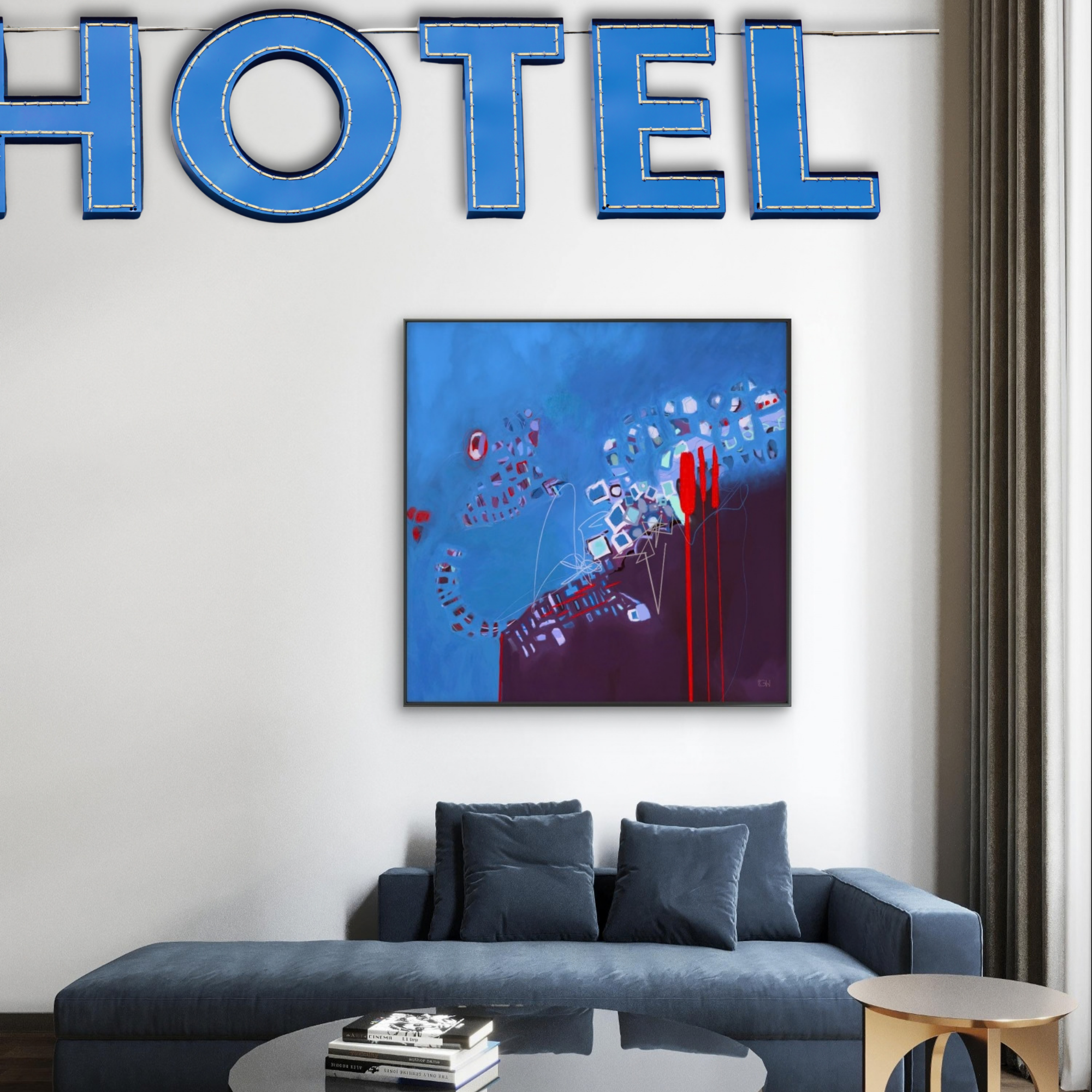 Modern hotel lobby featuring a large abstract painting called 'Life Blueprint' by Emily Whitish, hanging above a blue velvet sectional sofa, a black coffee table with books, a small wooden side table.