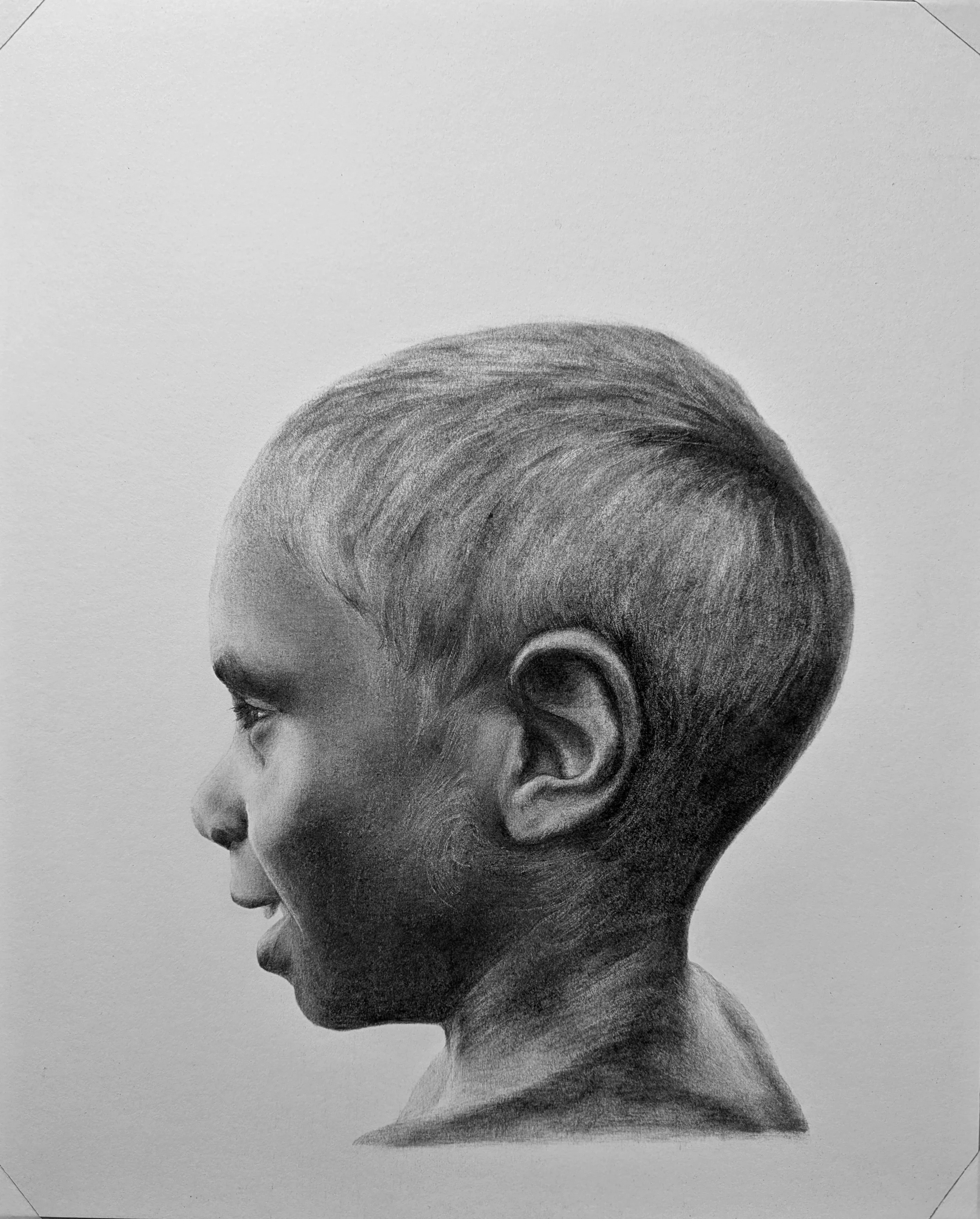A black and white photorealistic charcoal drawing of a young boy's side profile focusing on the head and upper neck, with detailed hair and facial features.