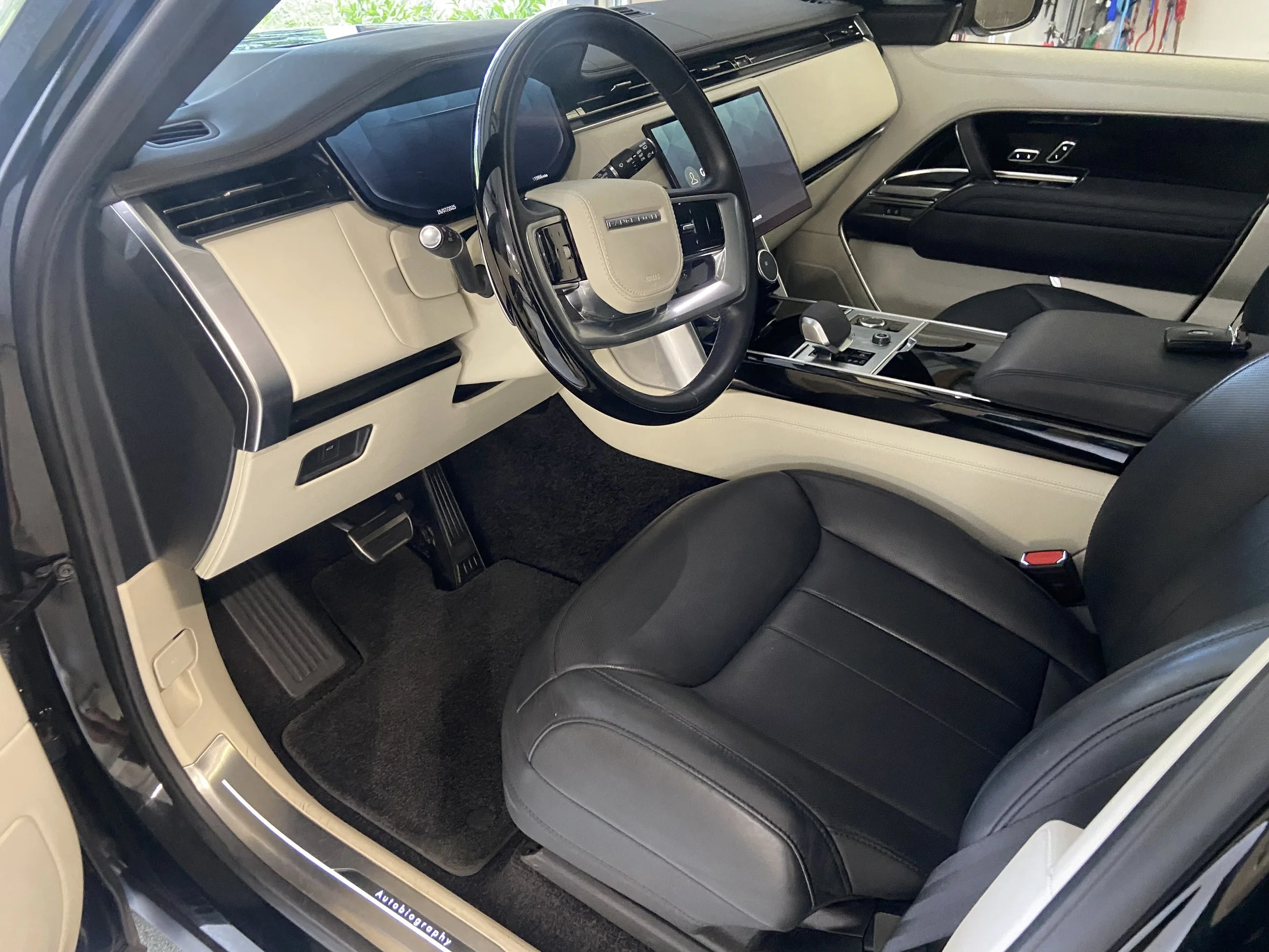 The interior of a modern vehicle, showing the dashboard, steering wheel, and front seats. The dashboard features a large digital display, and the steering wheel has multiple controls. The seats are upholstered in black and gray leather.