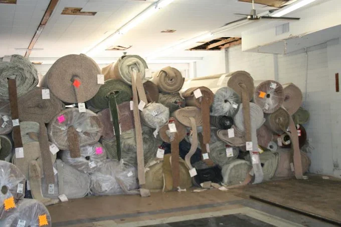 Storage of rolled carpets and rugs stacked in a warehouse.