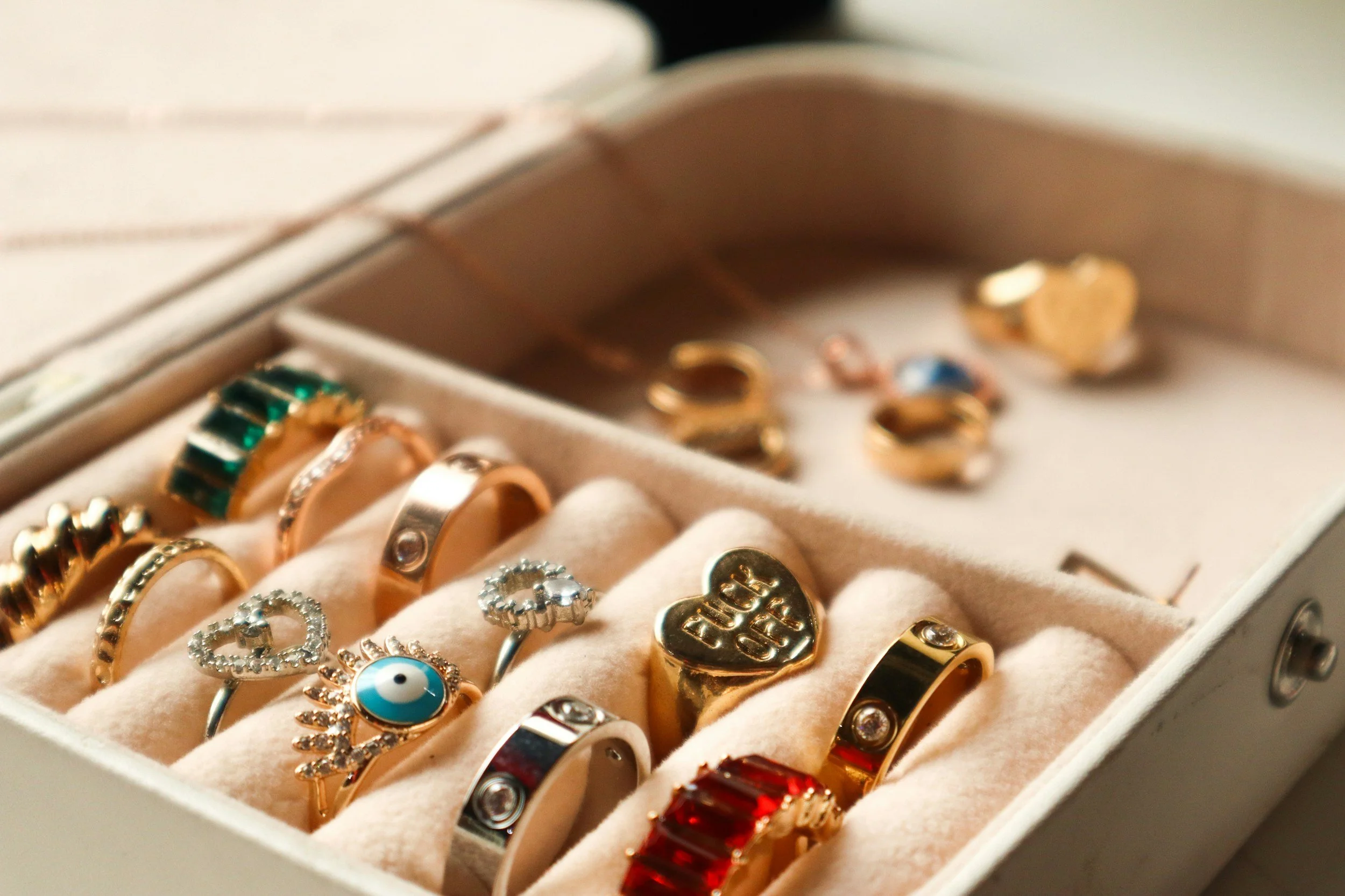Close-up of a jewelry box containing various gold and silver rings, some with gemstones and decorative designs.